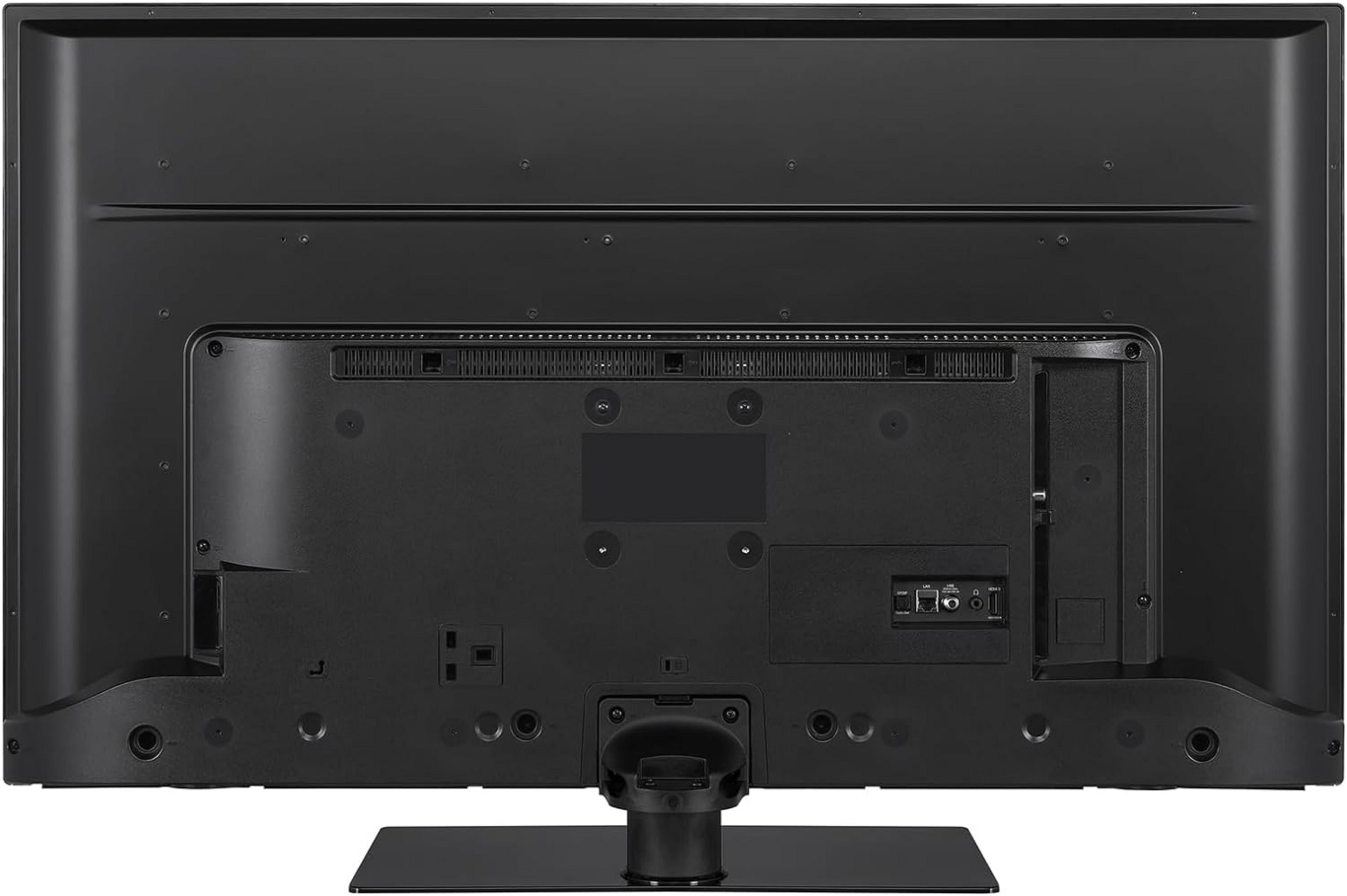 Vista trasera de un televisor negro con puertos y un soporte.