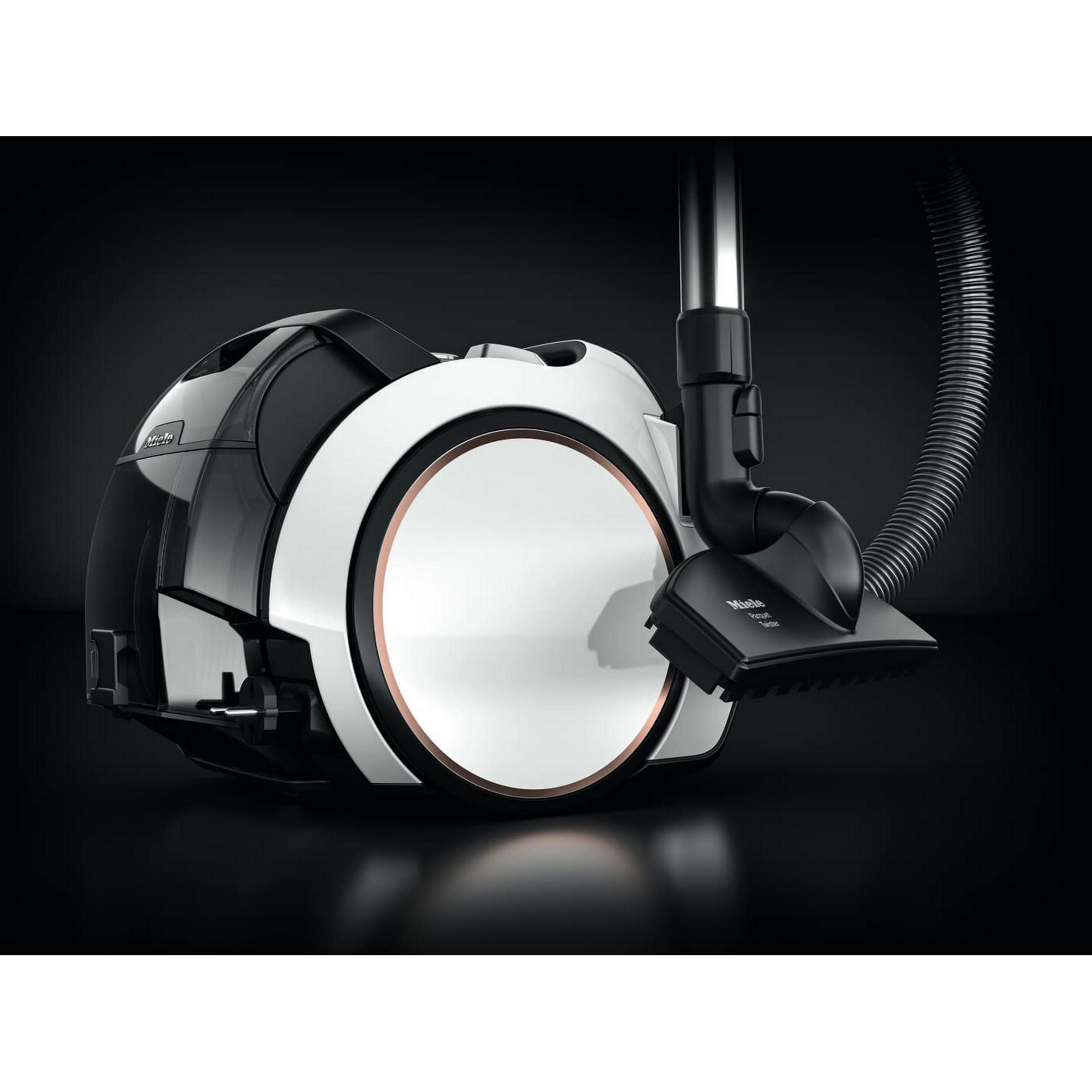 Un aspirapolvere Miele bianco e nero con tubo e spazzola su sfondo nero.