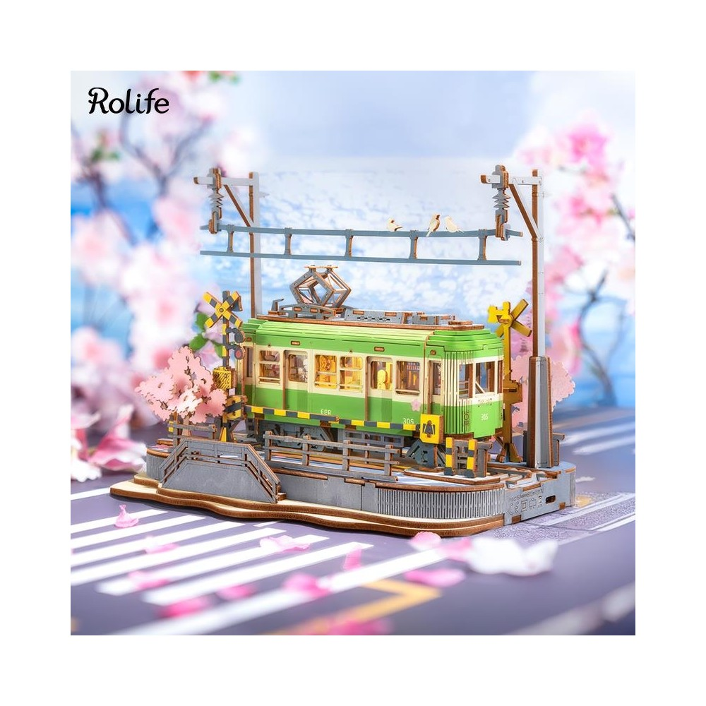 Grüne Modelleisenbahn auf Gleisen mit Kirschblüten und Ampeln.