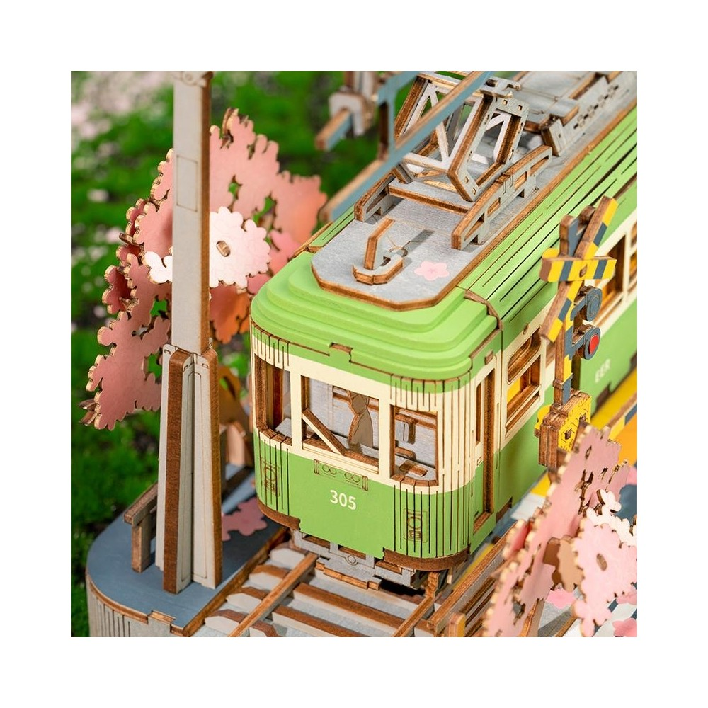 Ein hölzernes Modell einer grünen Straßenbahn mit Kirschblüten und einem Bahnübergang.