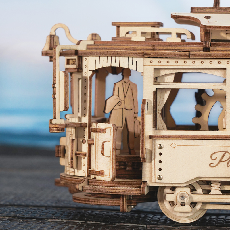 Holzmodell einer Straßenbahn mit Figur, die Koffer trägt.