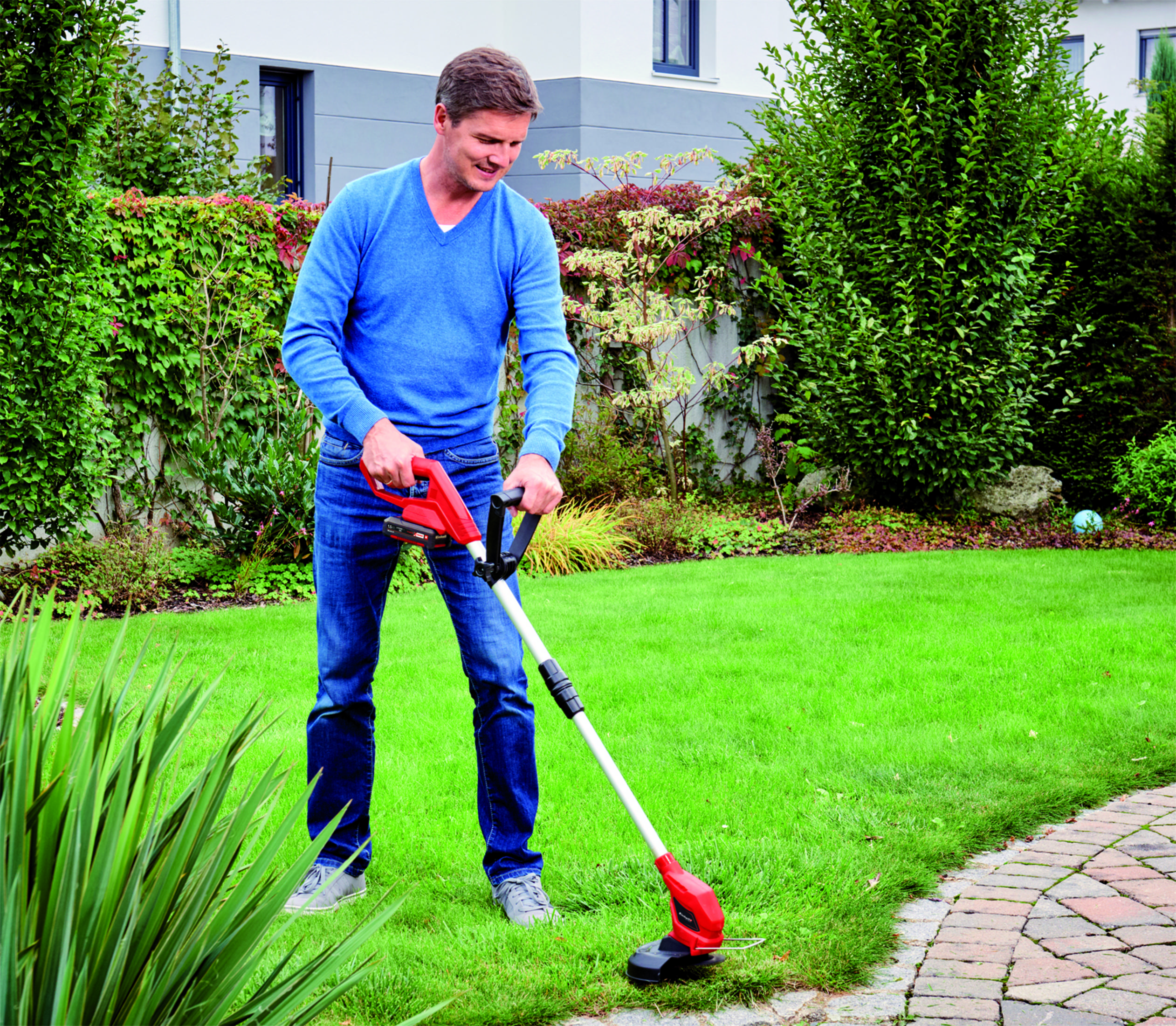 Mann trimmt Rasenkante mit Heckenschere im Garten
