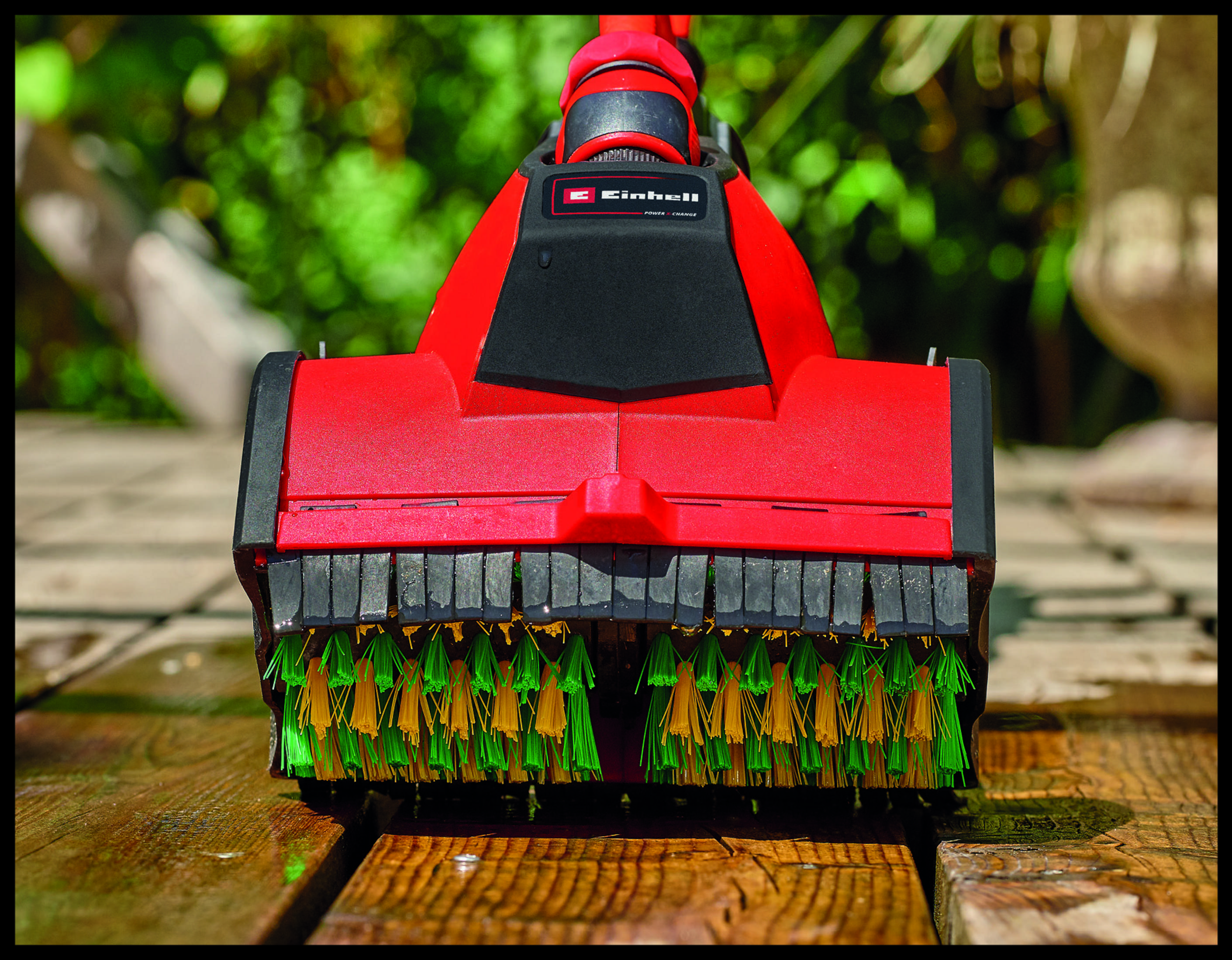 Ein roter Einhell Reiniger mit grünen und gelben Bürsten auf einer Holzoberfläche.