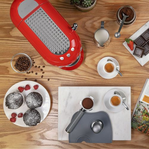 Macchina da caffè rossa con accessori: chicchi, torte, cioccolato, latte ed espresso.
