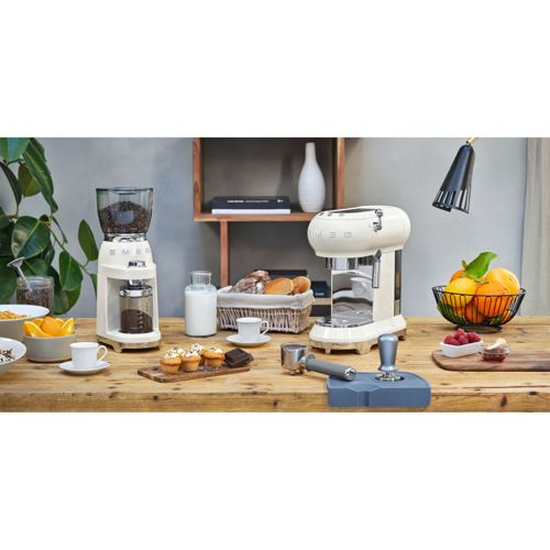 Un bancone da cucina bianco con macchina da caffè, macinino, pasticcini e frutta.