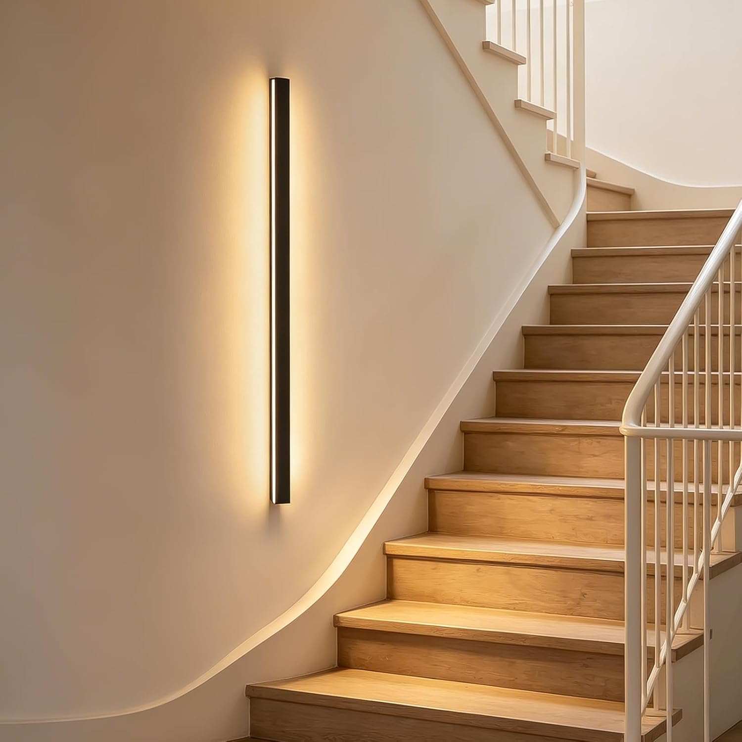 Una lunga e stretta applique illumina una scala in legno con ringhiera bianca.