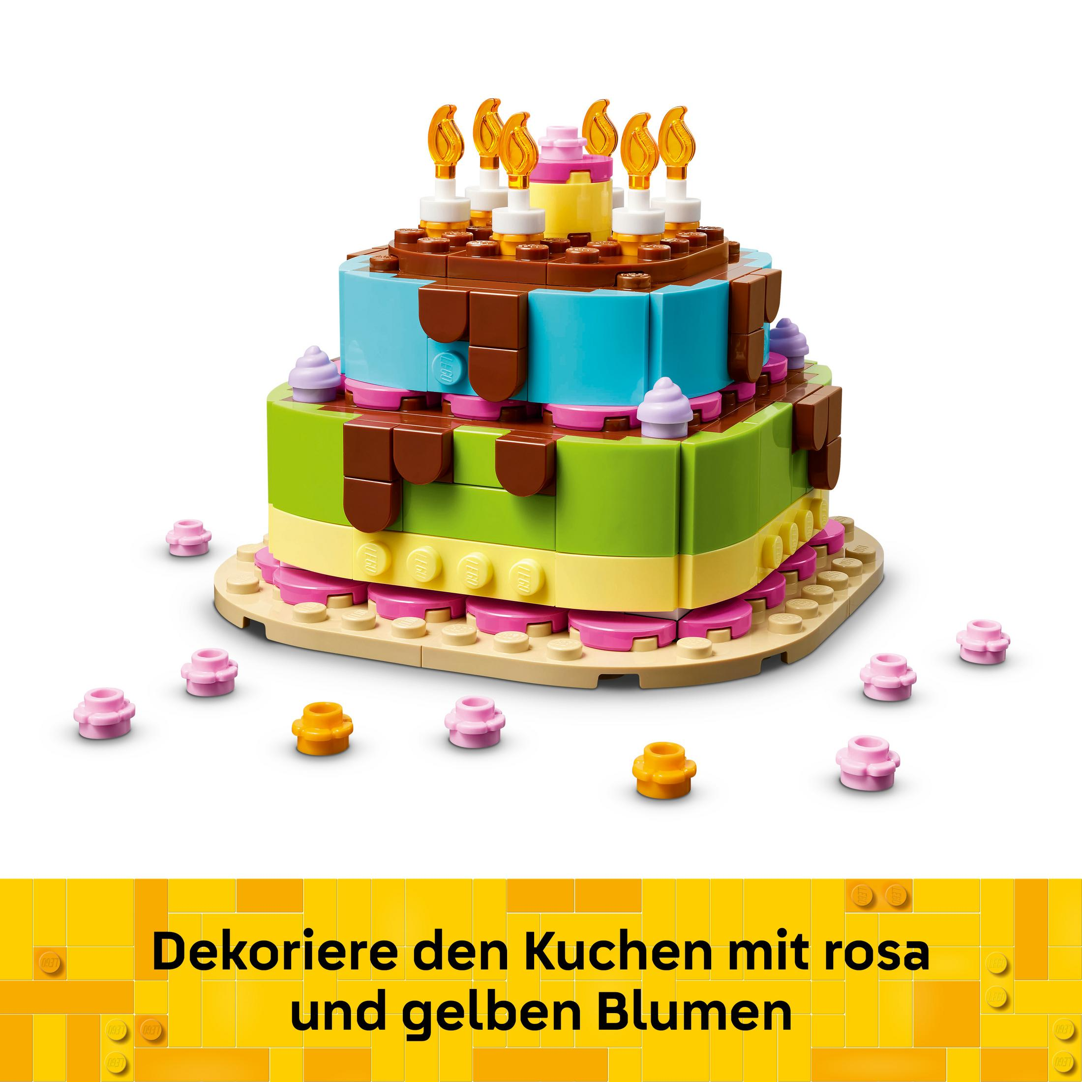Una torta di compleanno LEGO colorata con candele e fiori.