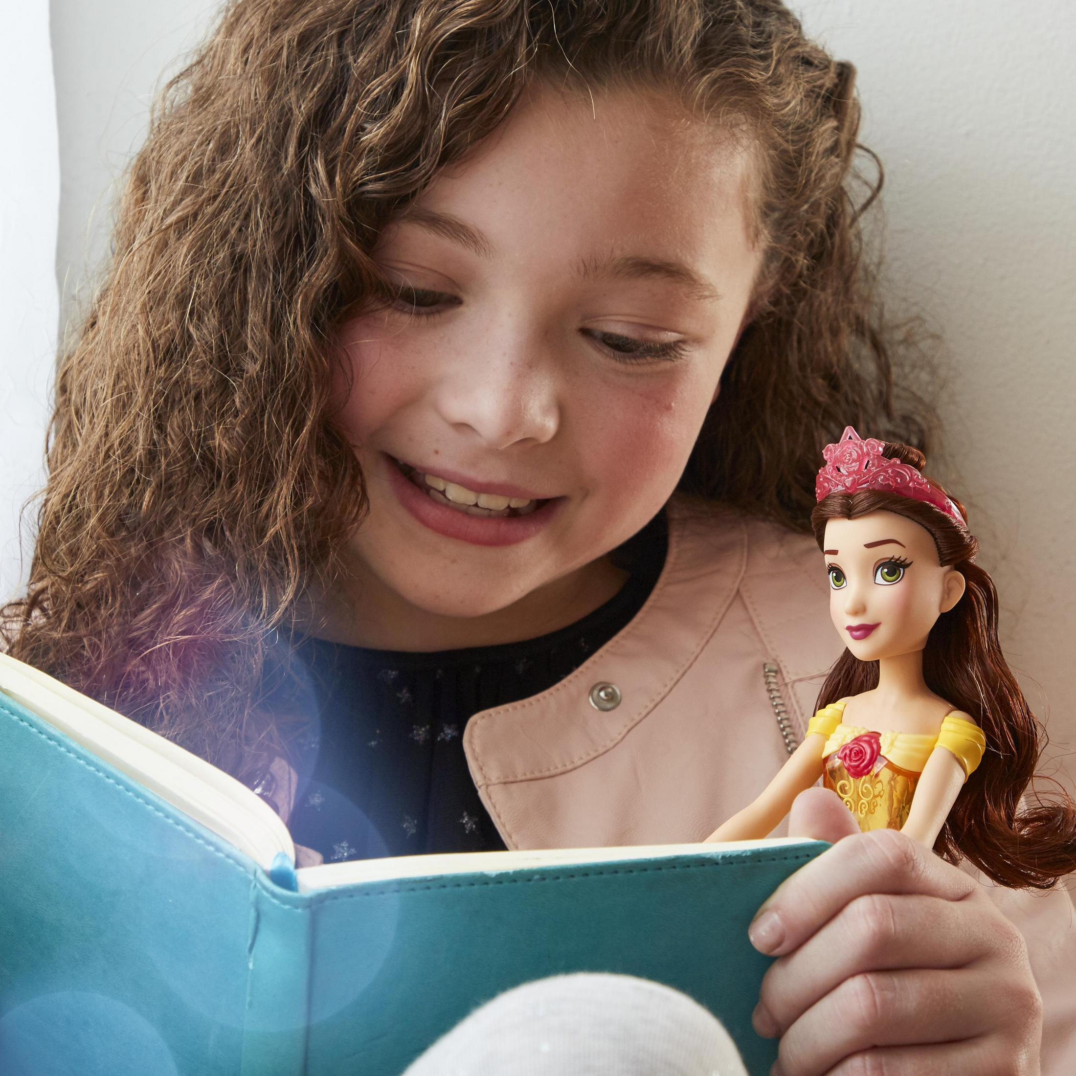 Una ragazza legge un libro con una bambola che indossa una corona.