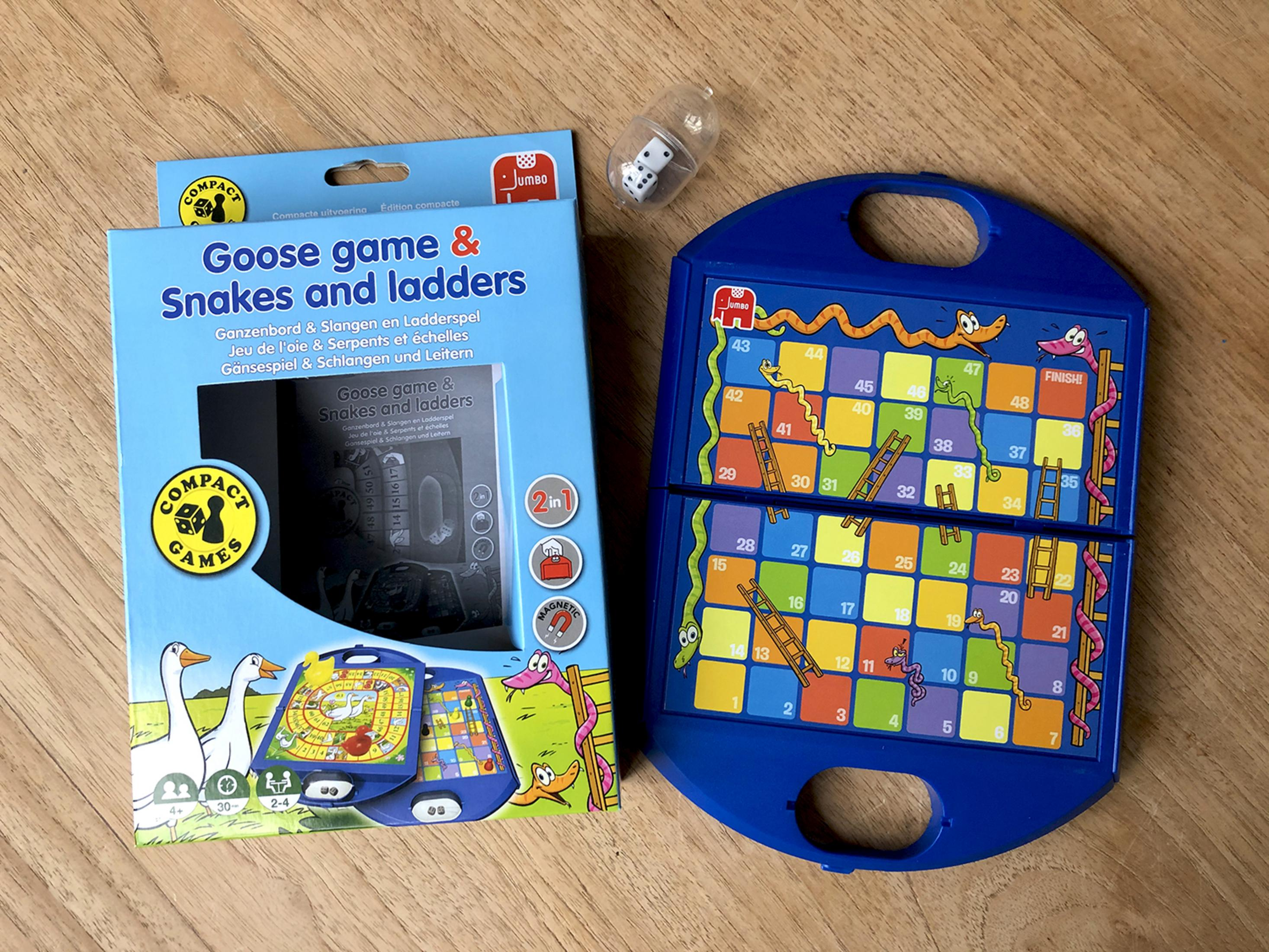 Brettspiel 'Leiter und Schlange' mit Spielbrett, Würfeln und Anleitung auf Holzhintergrund.