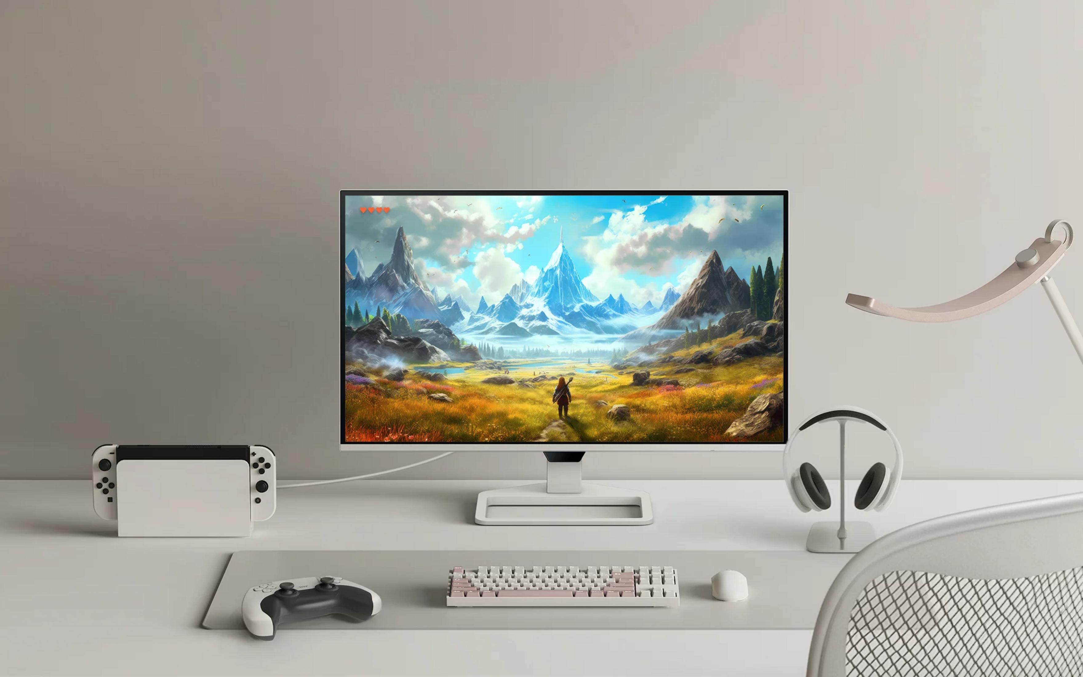 Un escritorio con un monitor que muestra un paisaje montañoso, junto a un Nintendo Switch, auriculares y teclado.