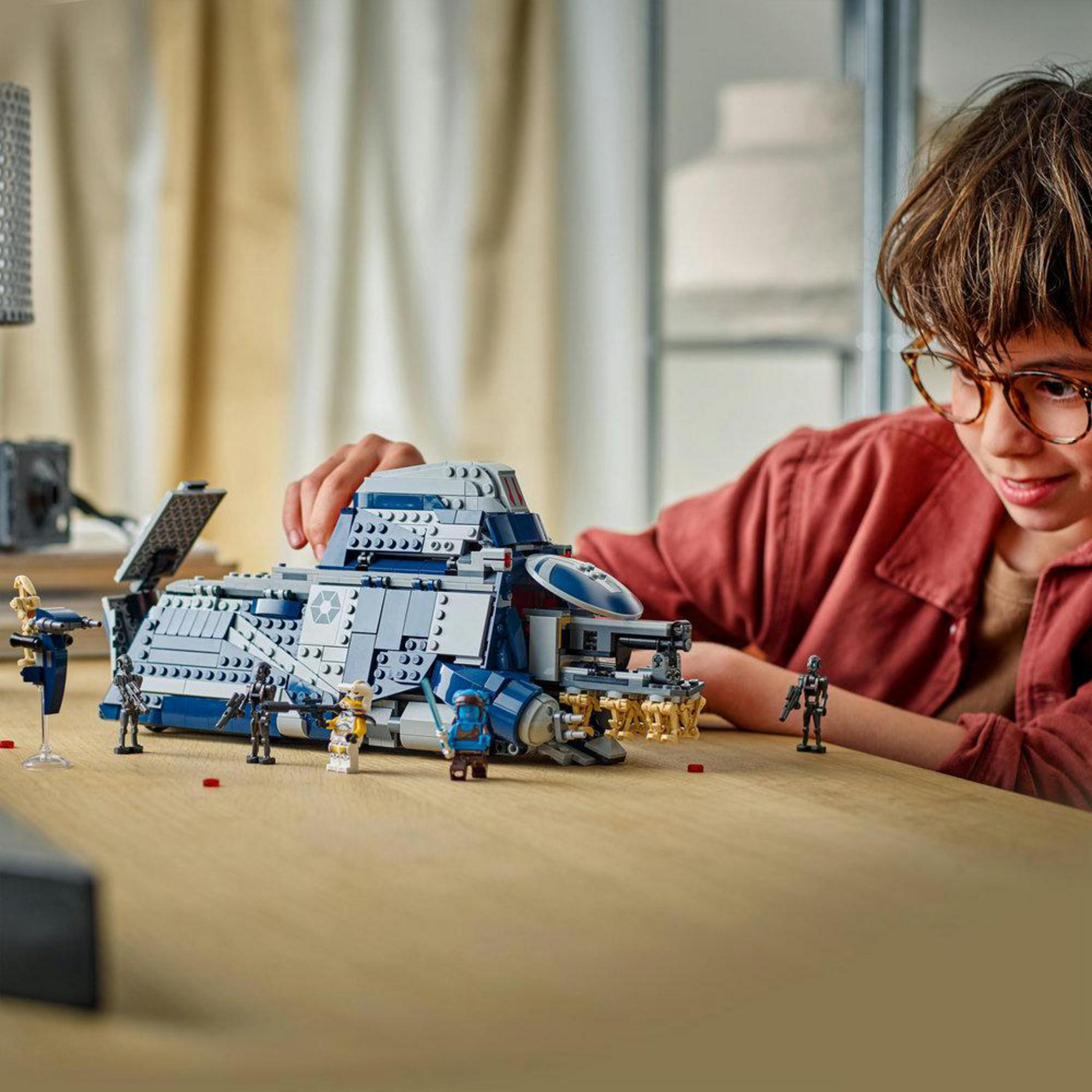 Un ragazzo con gli occhiali costruisce un'astronave Lego blu con figure.