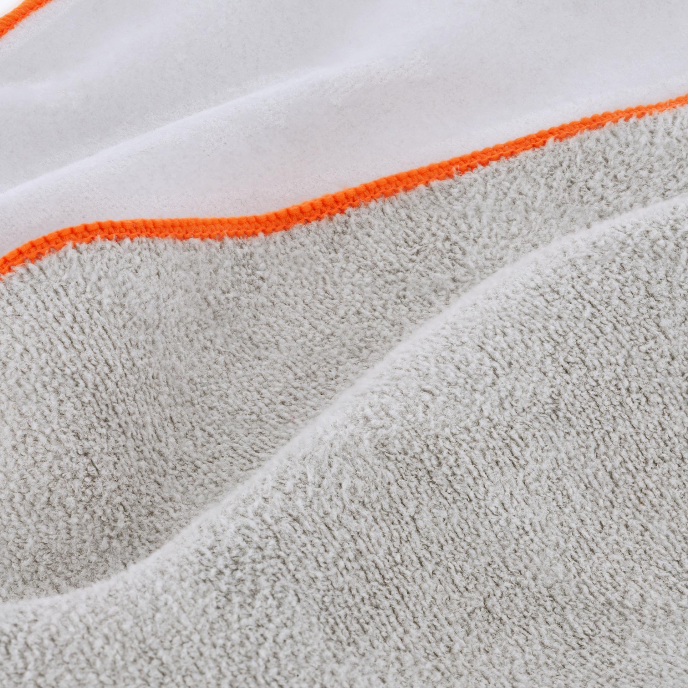 Grauer Frotteestoff mit weißer Innenseite und orangefarbener Einfassung. Detailaufnahme.