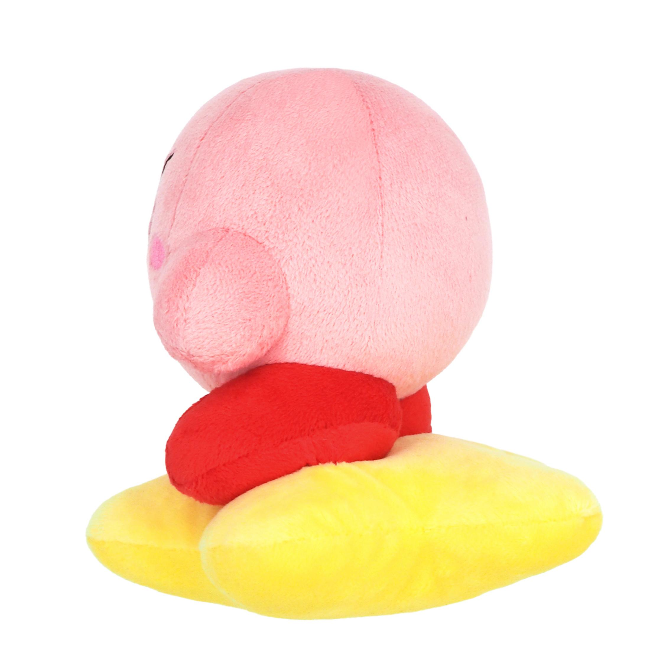 Une peluche rose de Kirby avec des joues rouges est assise sur un coussin jaune.