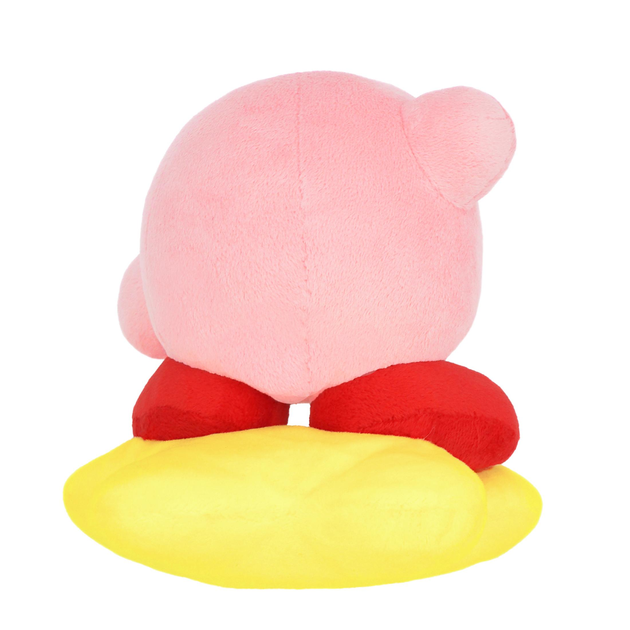 Une peluche rose de Kirby assise sur un coussin jaune.