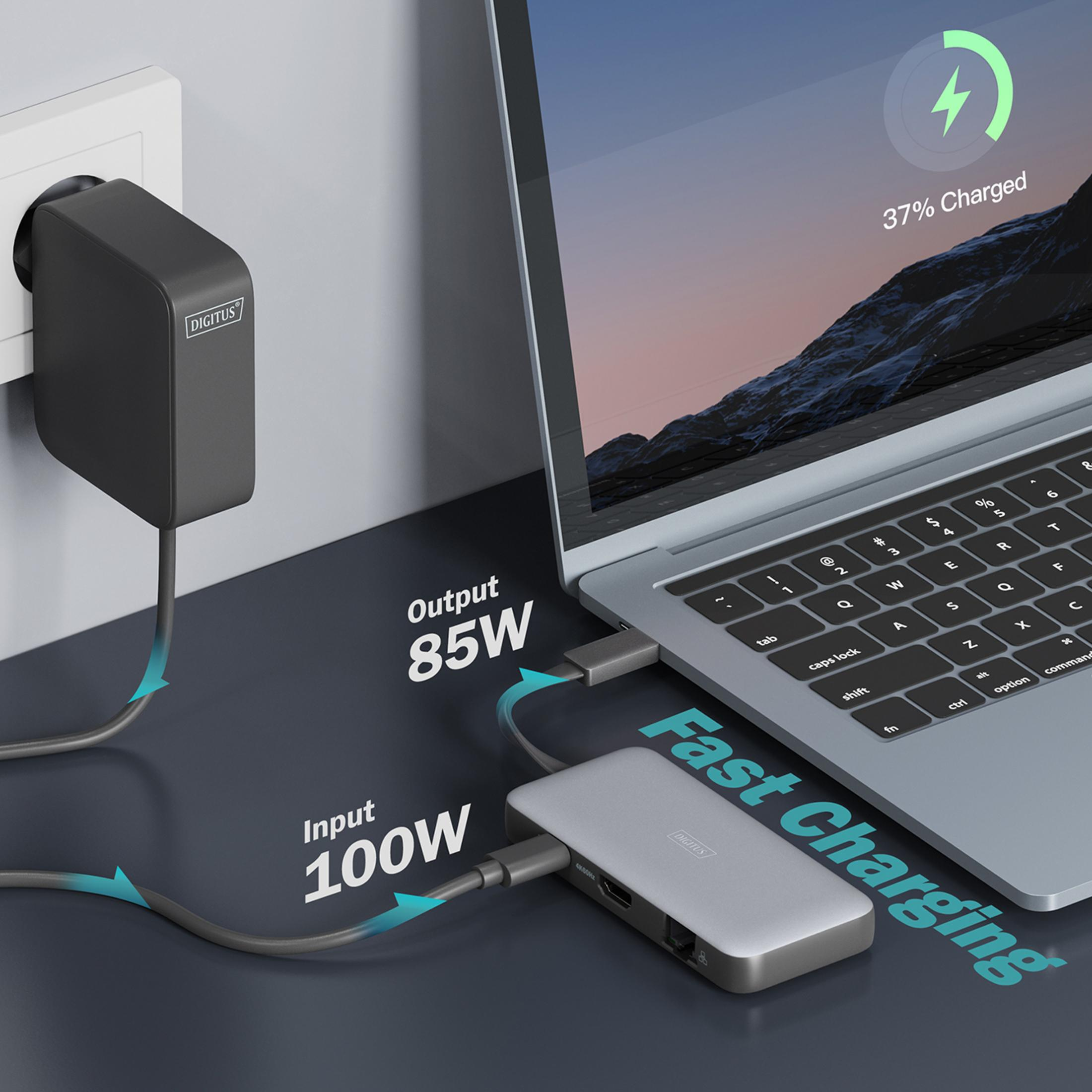 Ein schwarzer Netzstecker versorgt einen silbernen USB-C-Hub, der einen Laptop mit 85W versorgt.
