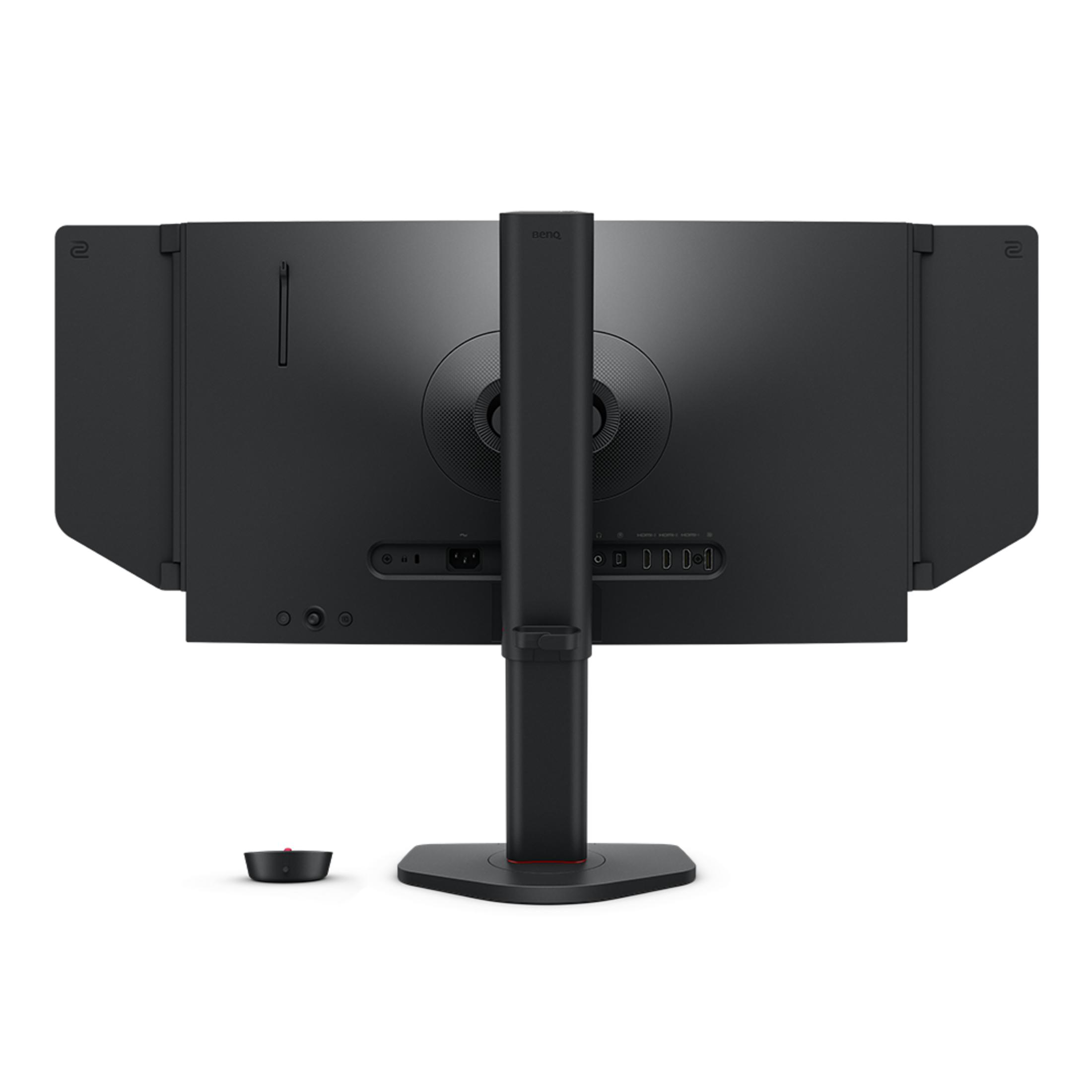 Parte trasera de un monitor negro con soporte y puertos. Una pequeña unidad de control negra.