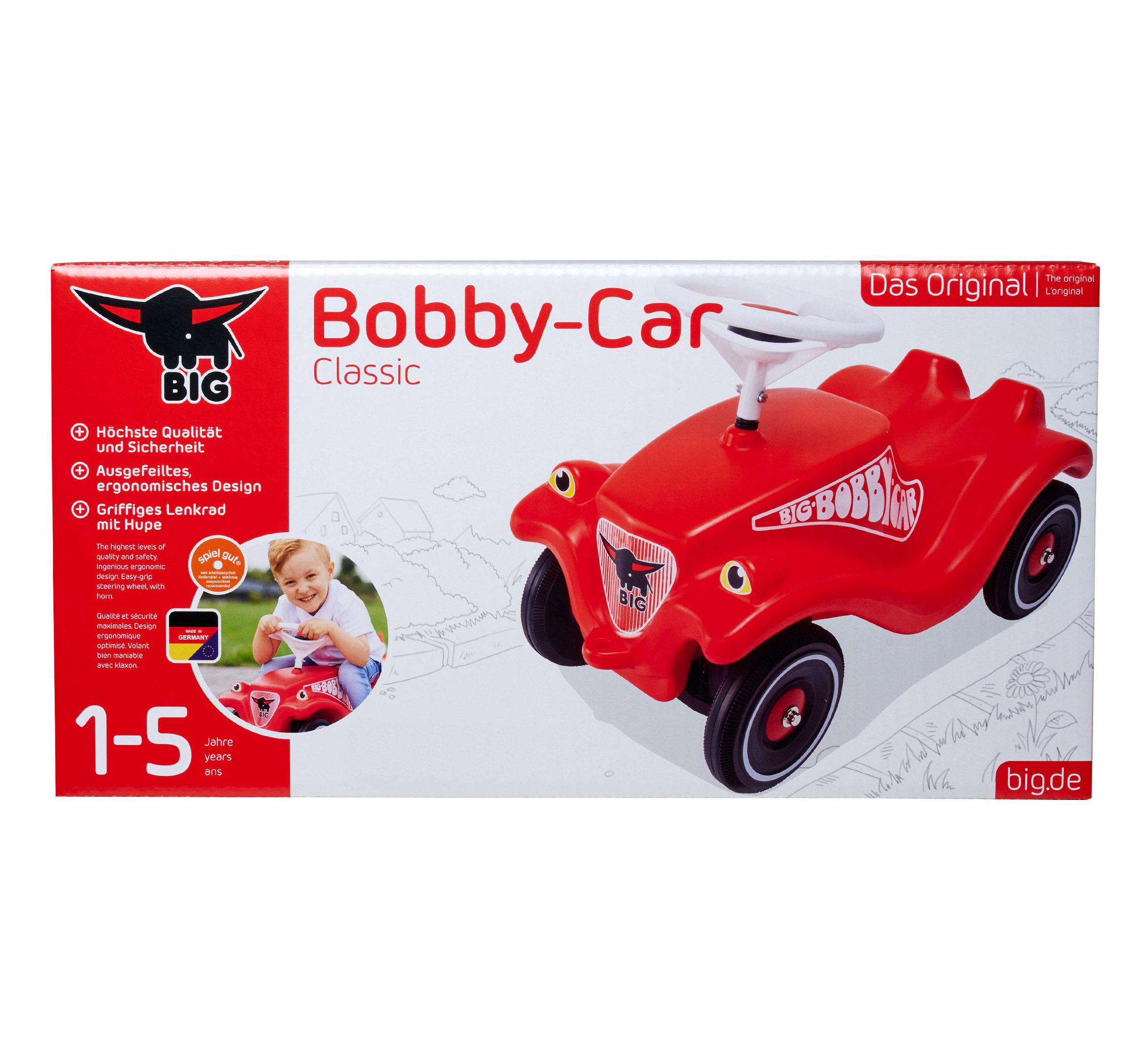 Bobby-Car Classic rosso con volante bianco e un bambino seduto sopra.