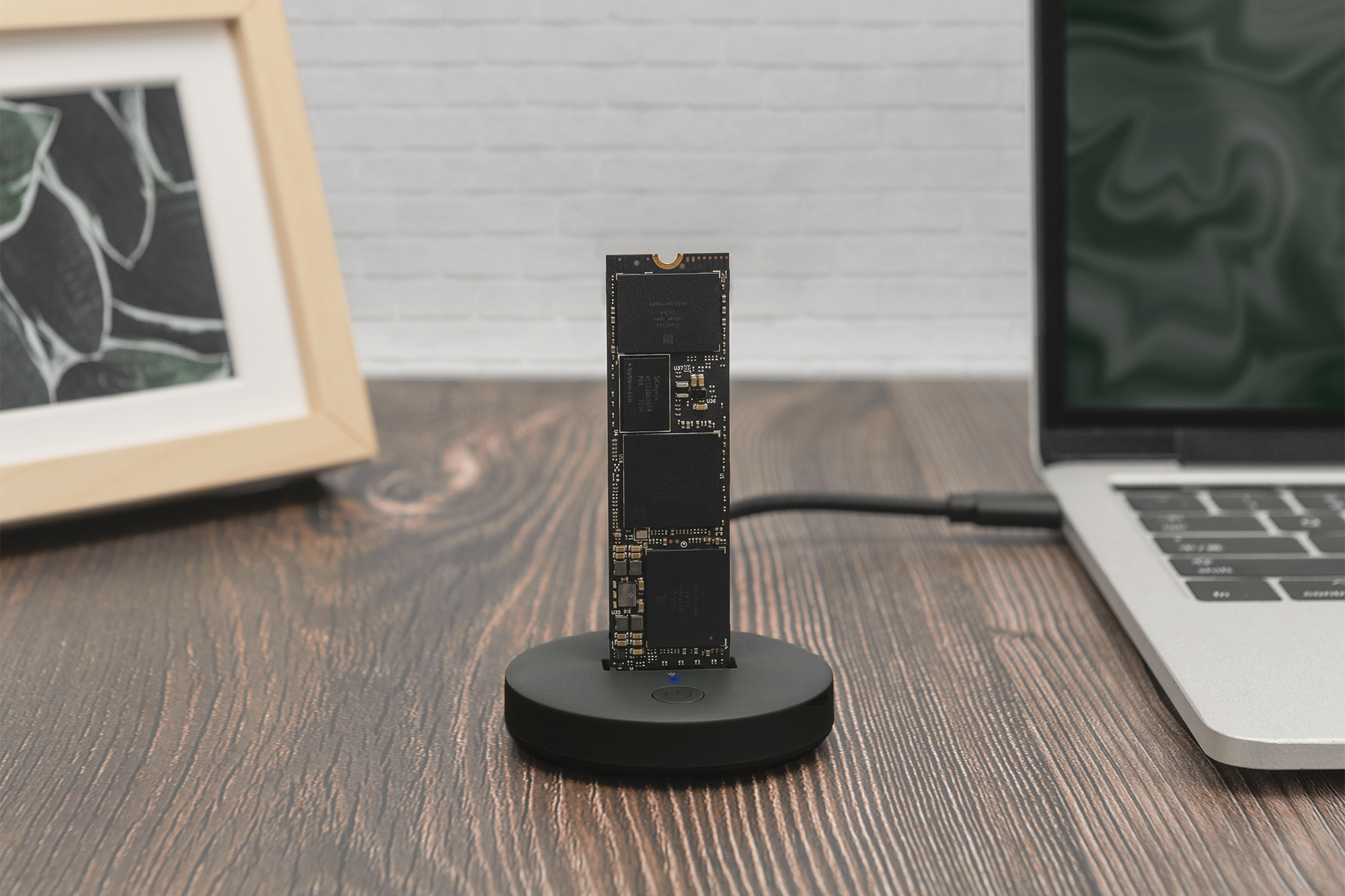 Un'unità SSD M.2 su un supporto nero accanto a un laptop.