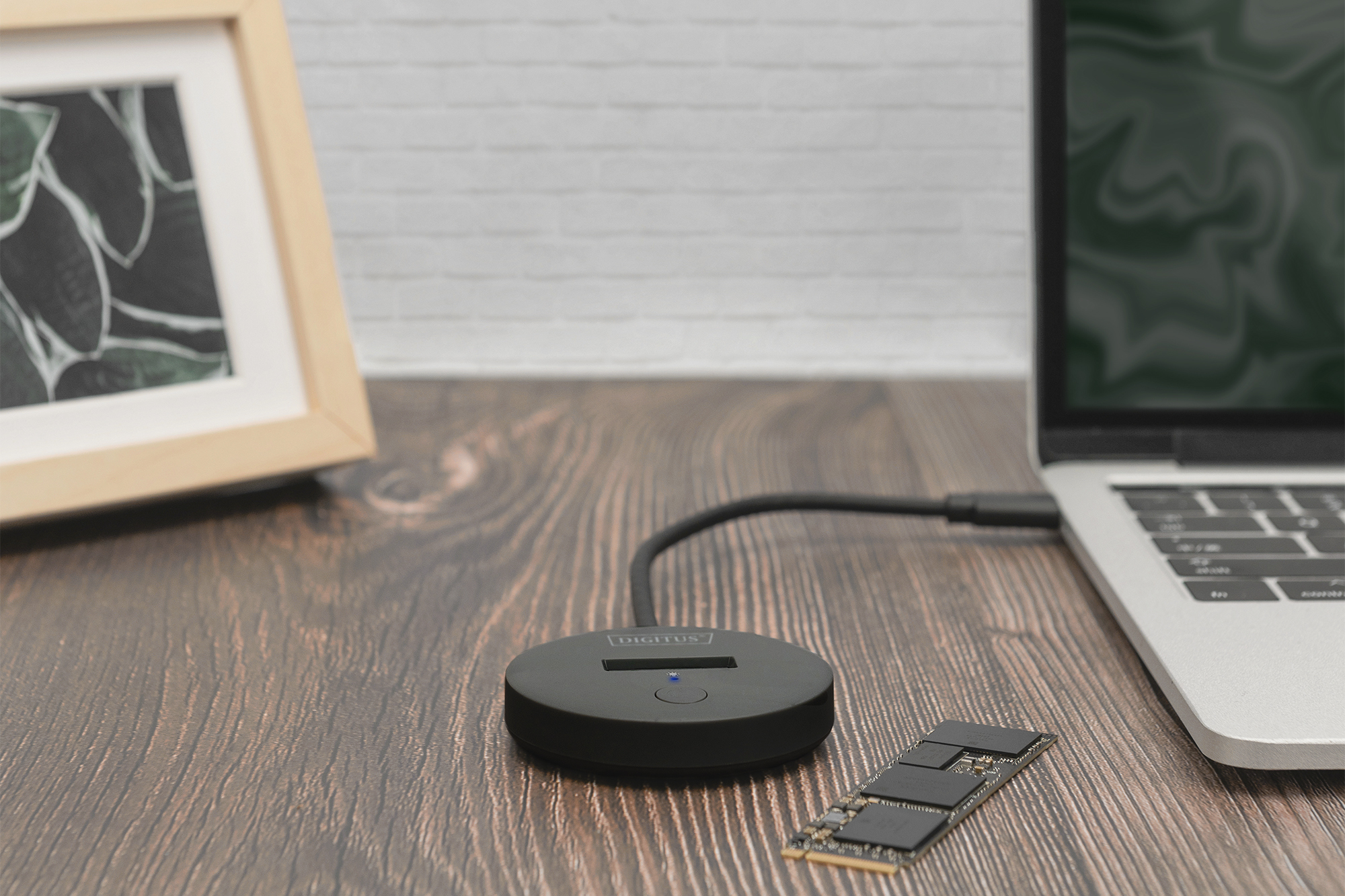 Un enclosure SSD esterno nero si collega a un laptop. Un'unità SSD riposa nelle vicinanze.