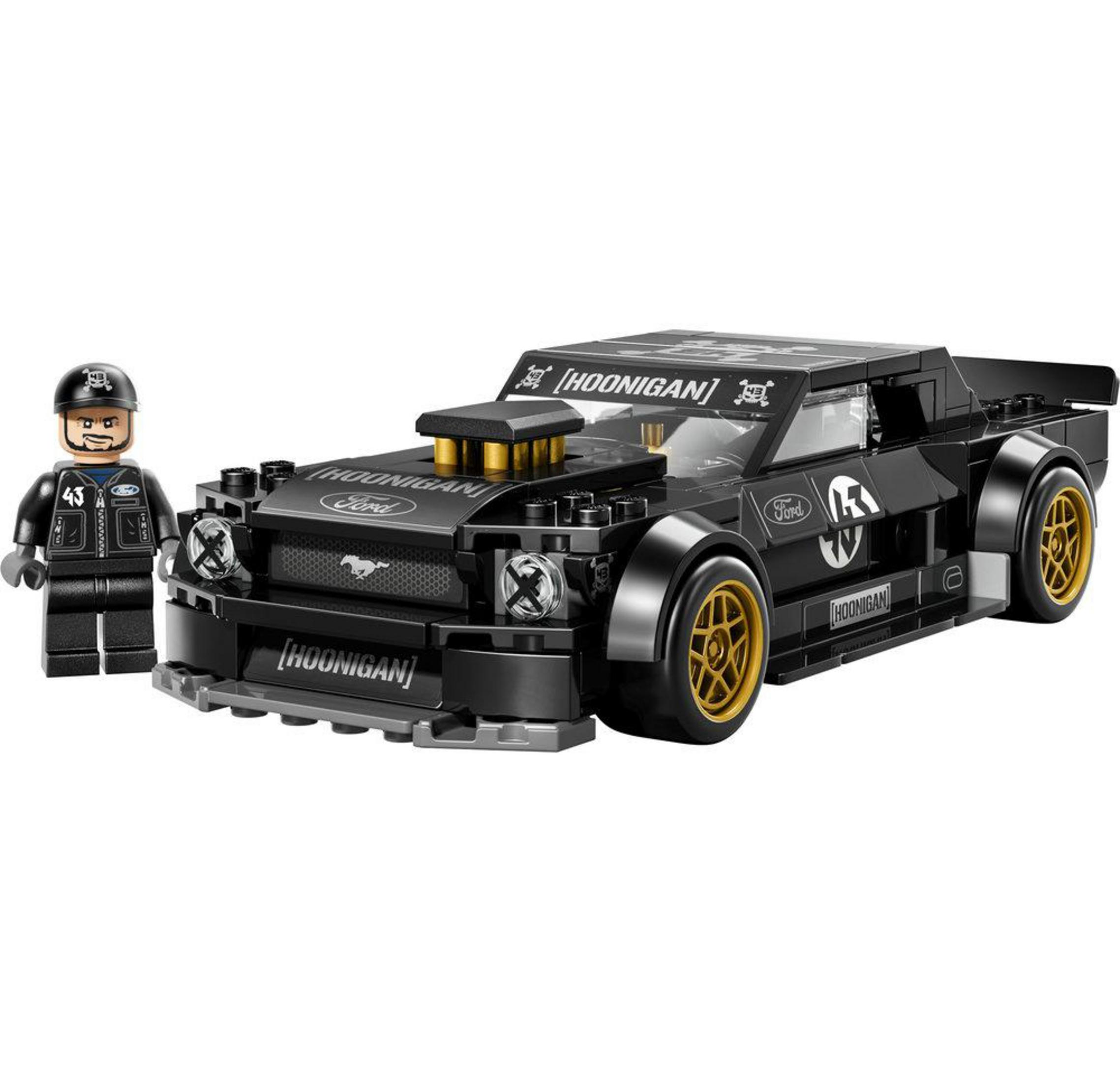 Figurka kierowcy stoi obok czarnego samochodu wyścigowego Ford Mustang Hoonigan ze złotymi felgami.