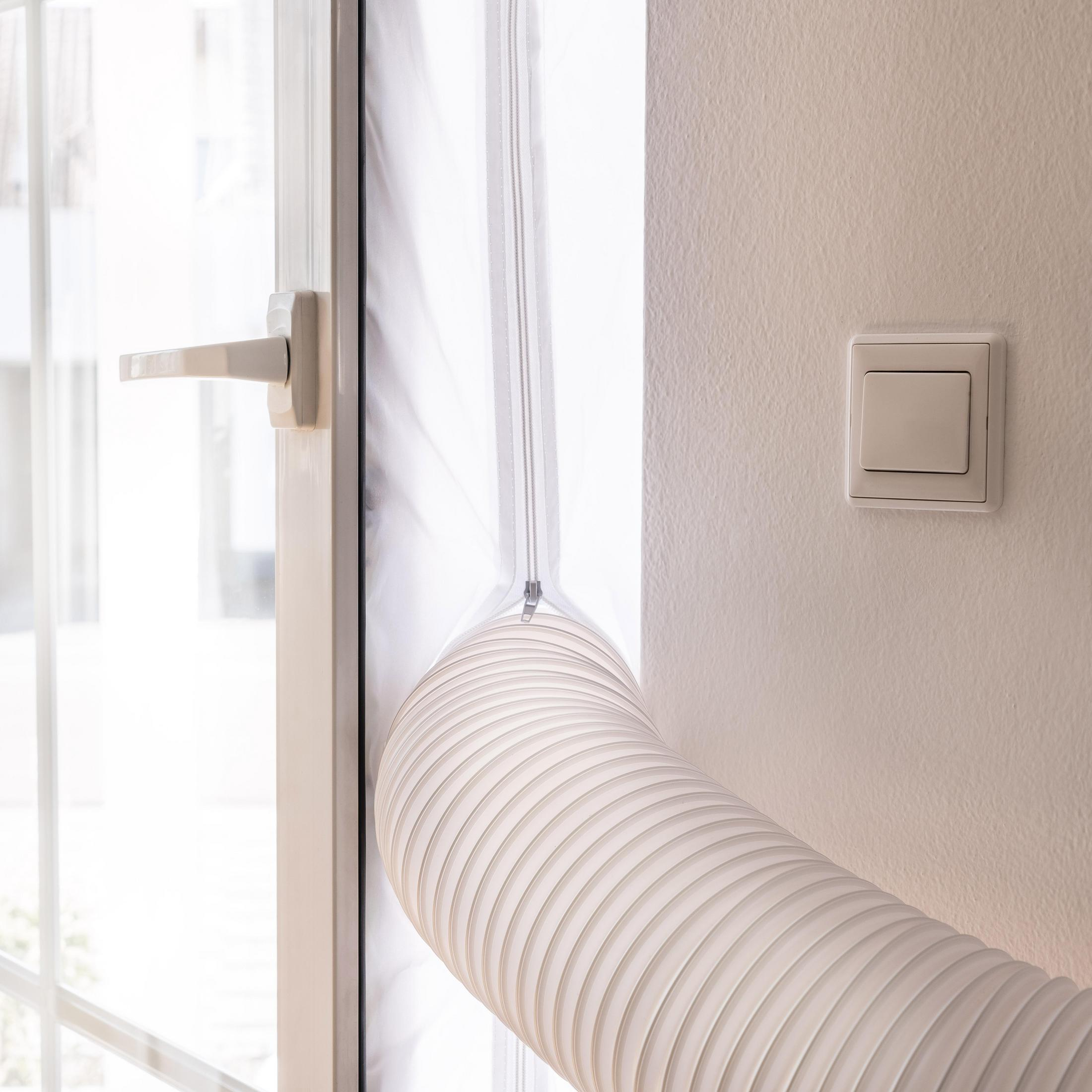 Ein weißer flexibler Schlauch ragt aus einem Fensterrahmen. Ein Lichtschalter ist an der Wand.