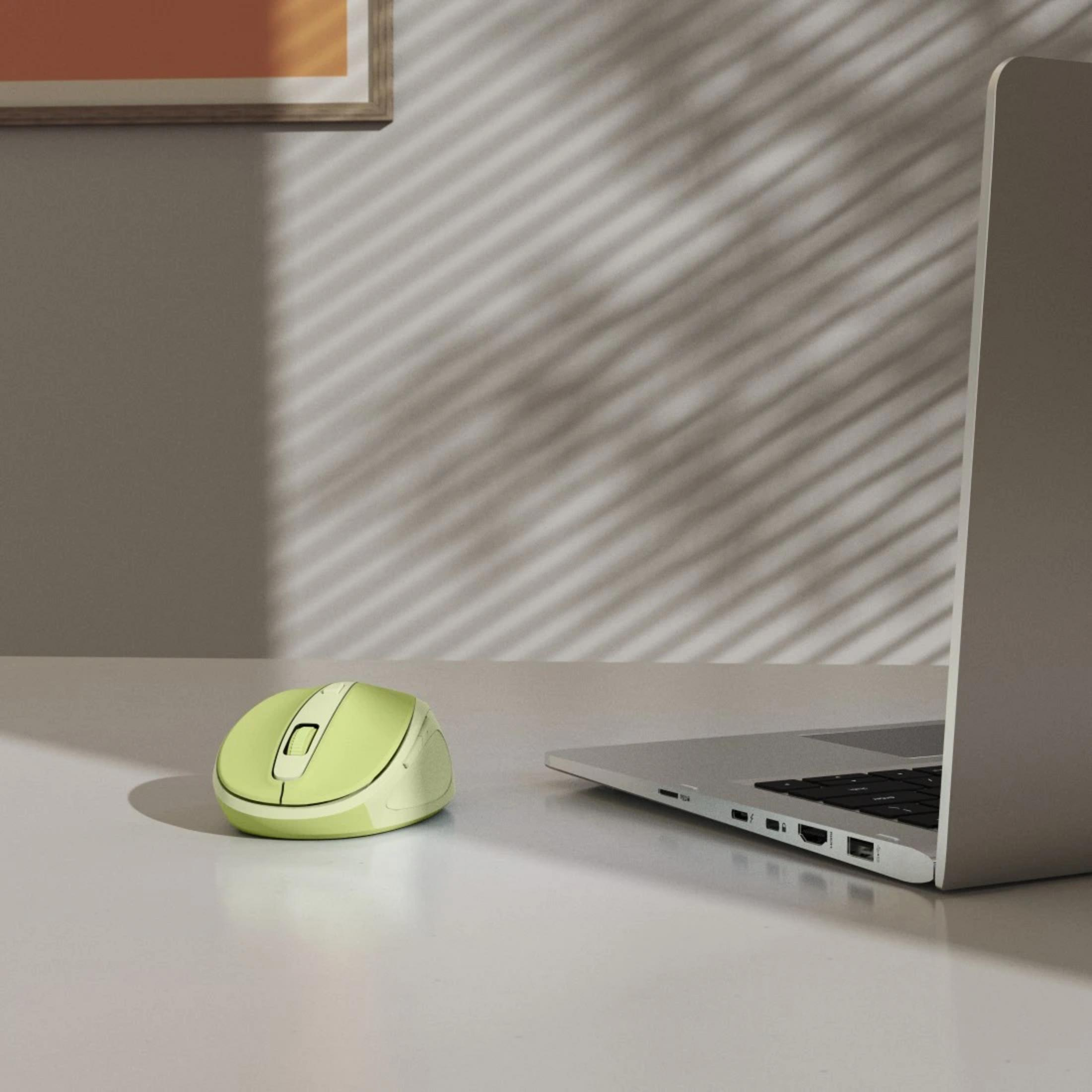 Un mouse verde chiaro e un laptop su una scrivania bianca.