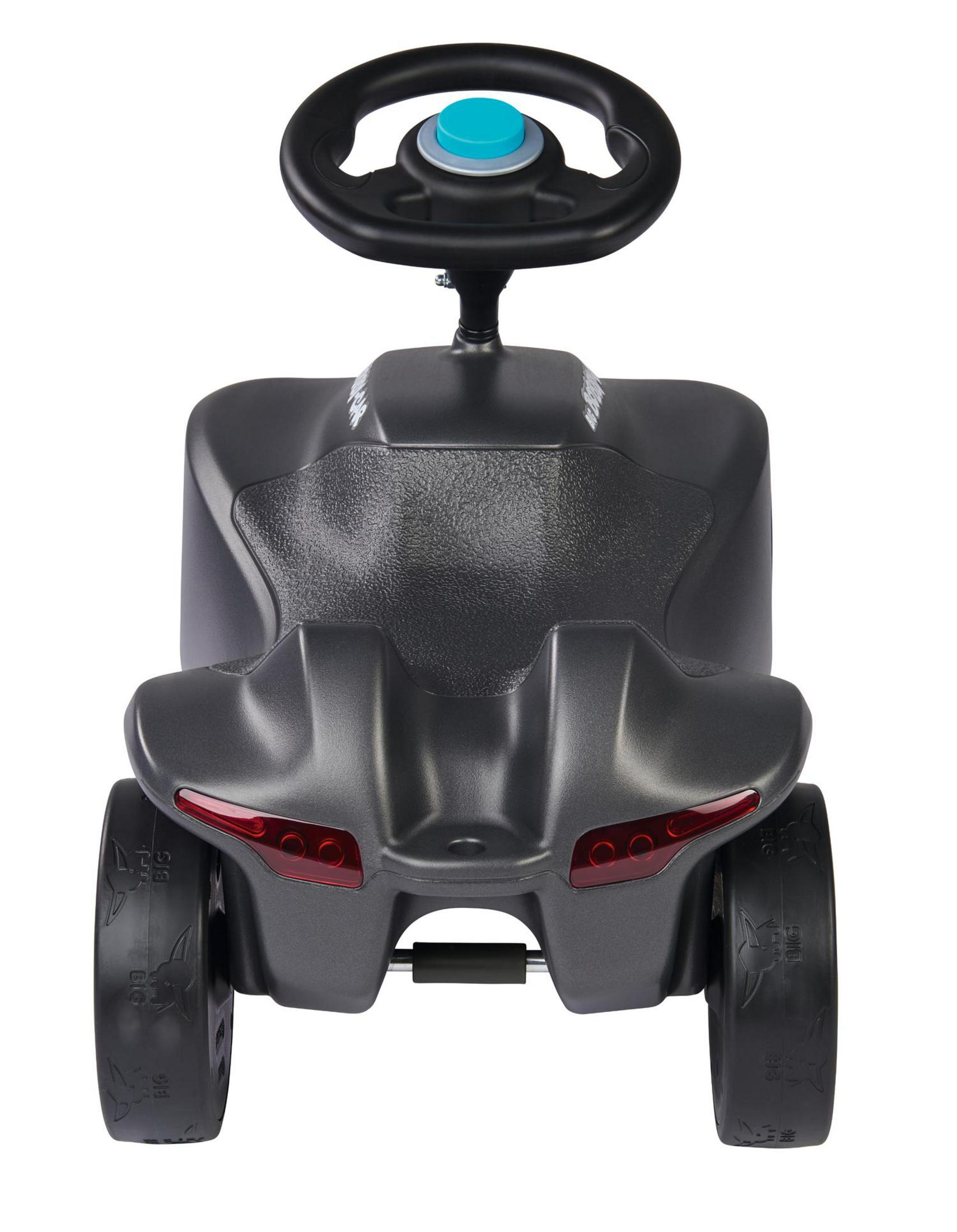 Ein graues Kinderfahrzeug mit schwarzem Lenkrad und blauer Hupe.