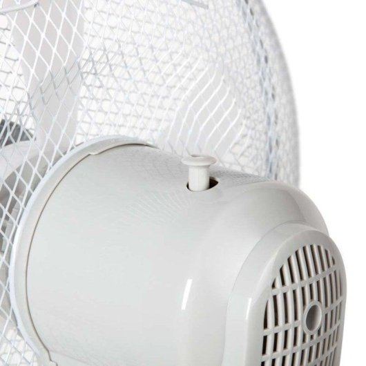 Primo piano di un motore di ventilatore elettrico bianco con griglia di sicurezza in metallo.