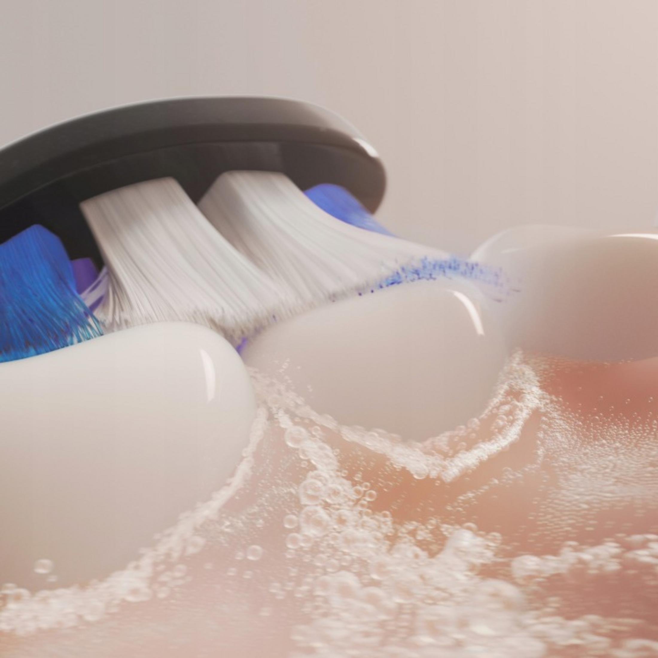 Spazzolino elettrico pulisce i denti con schiuma e bolle.