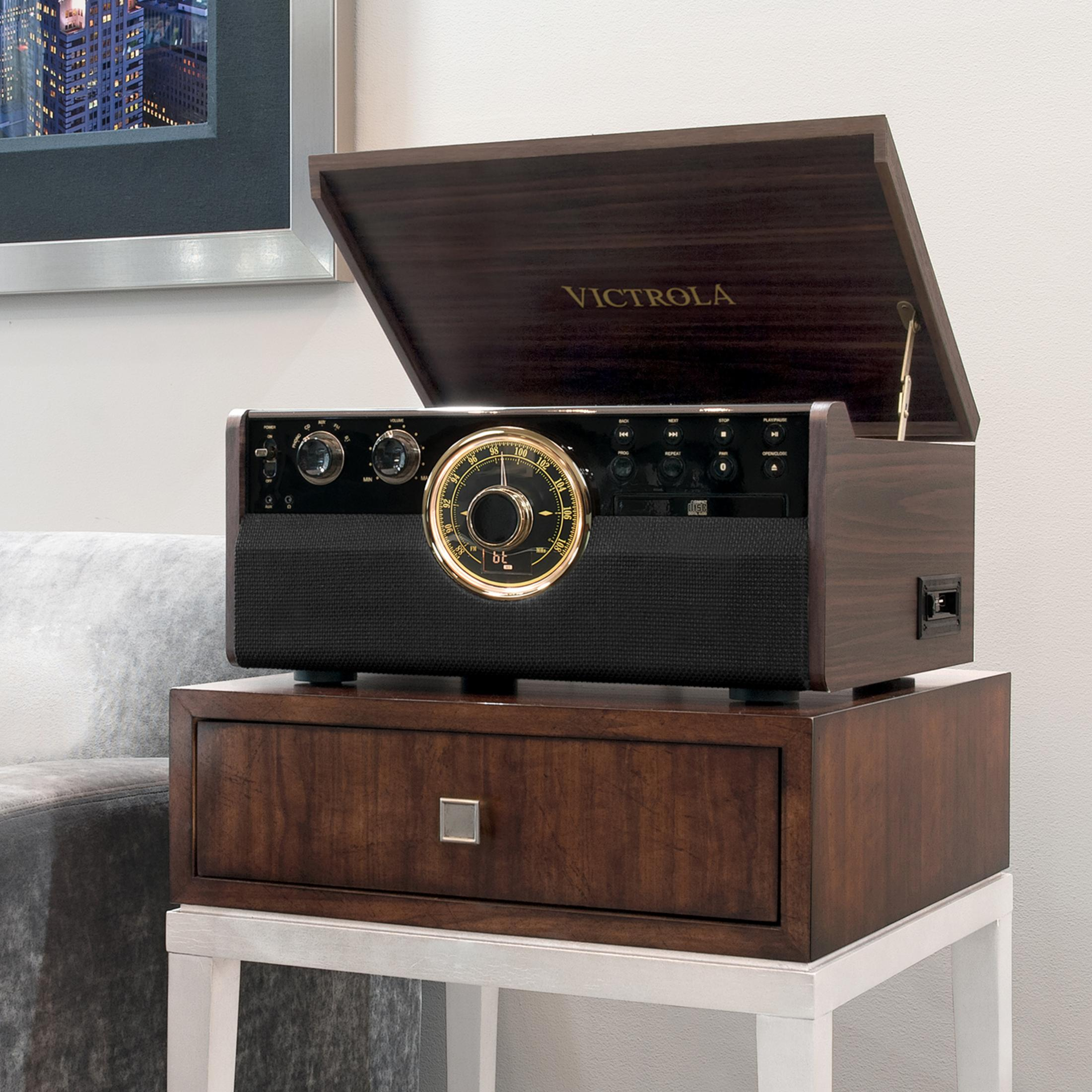 Un giradischi in legno con radio e lettore CD si trova su un cassetto.