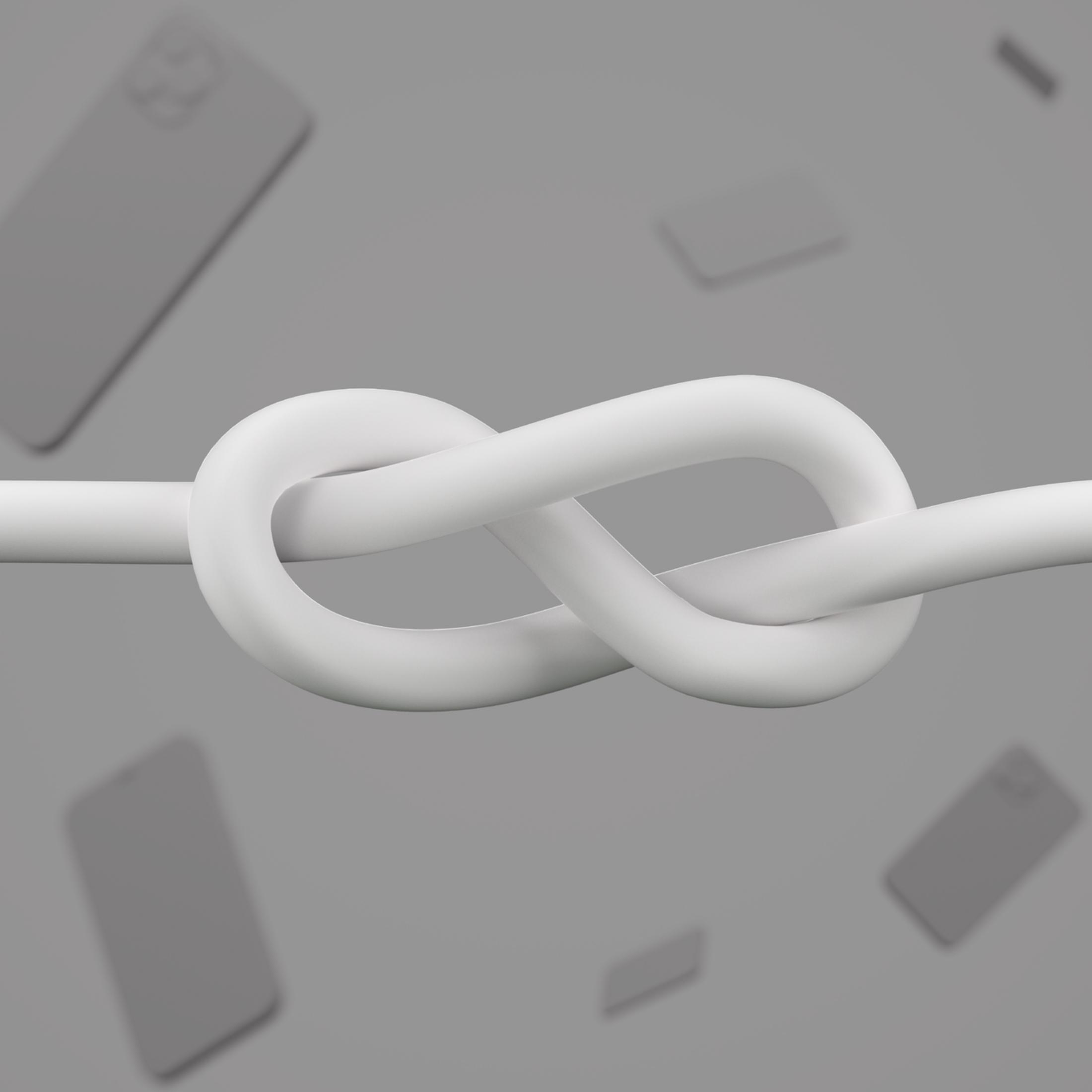 Ein weißes Kabel ist in einer Acht verknotet, mit verschwommenen Smartphones im Hintergrund.