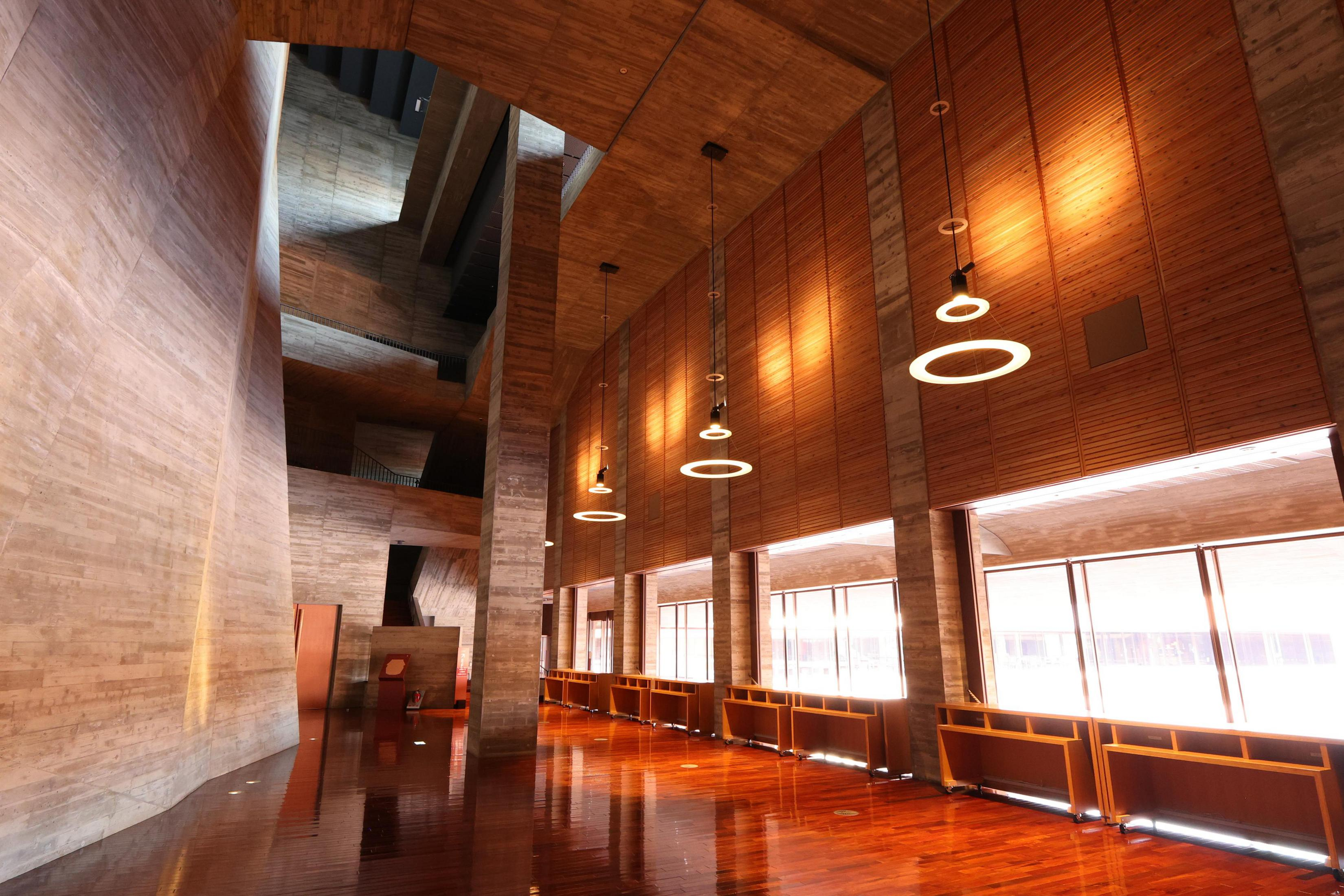 Intérieur d'un bâtiment moderne avec murs en béton, lambris et parquets brillants.