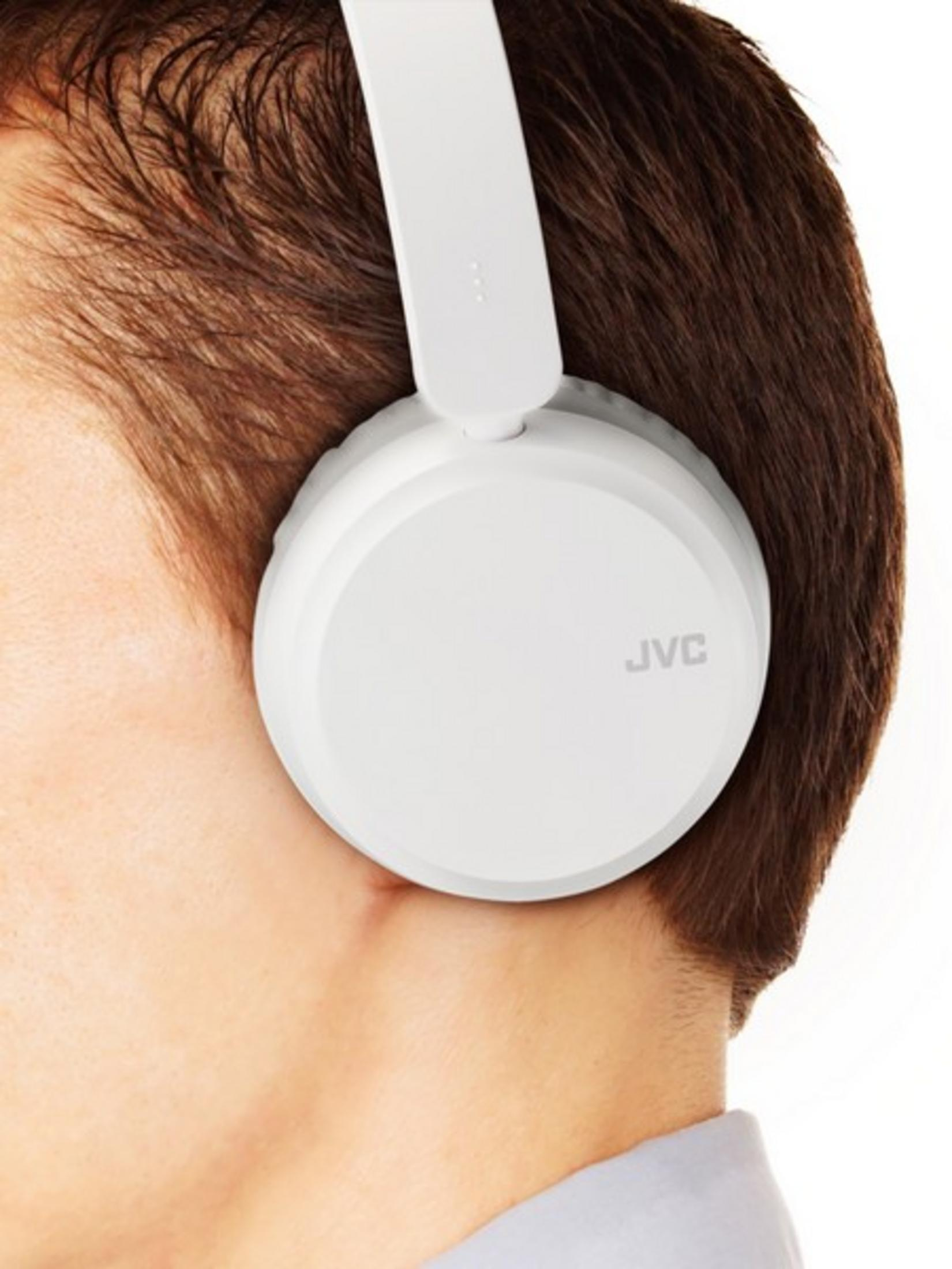 Un uomo con capelli castani indossa cuffie bianche JVC.