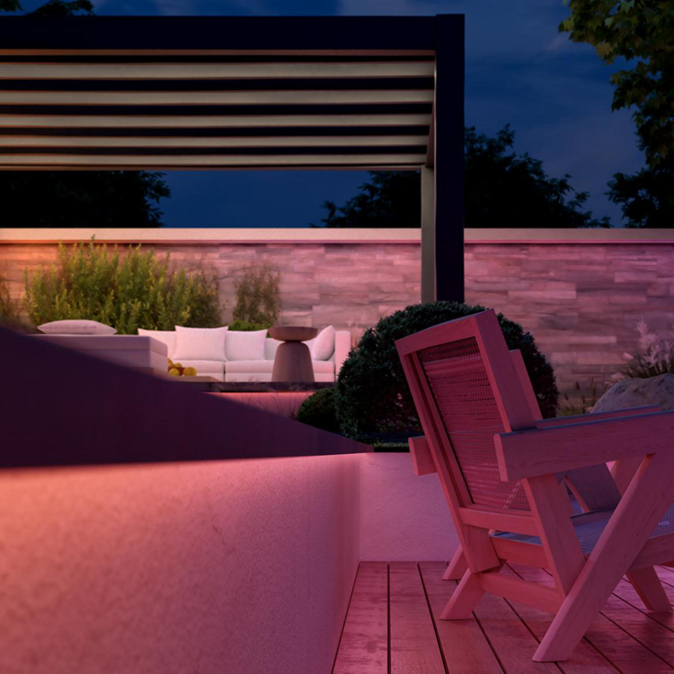 Außenpatio mit moderner Pergola, weißem Sofa und Holzstühlen in der Dämmerung.