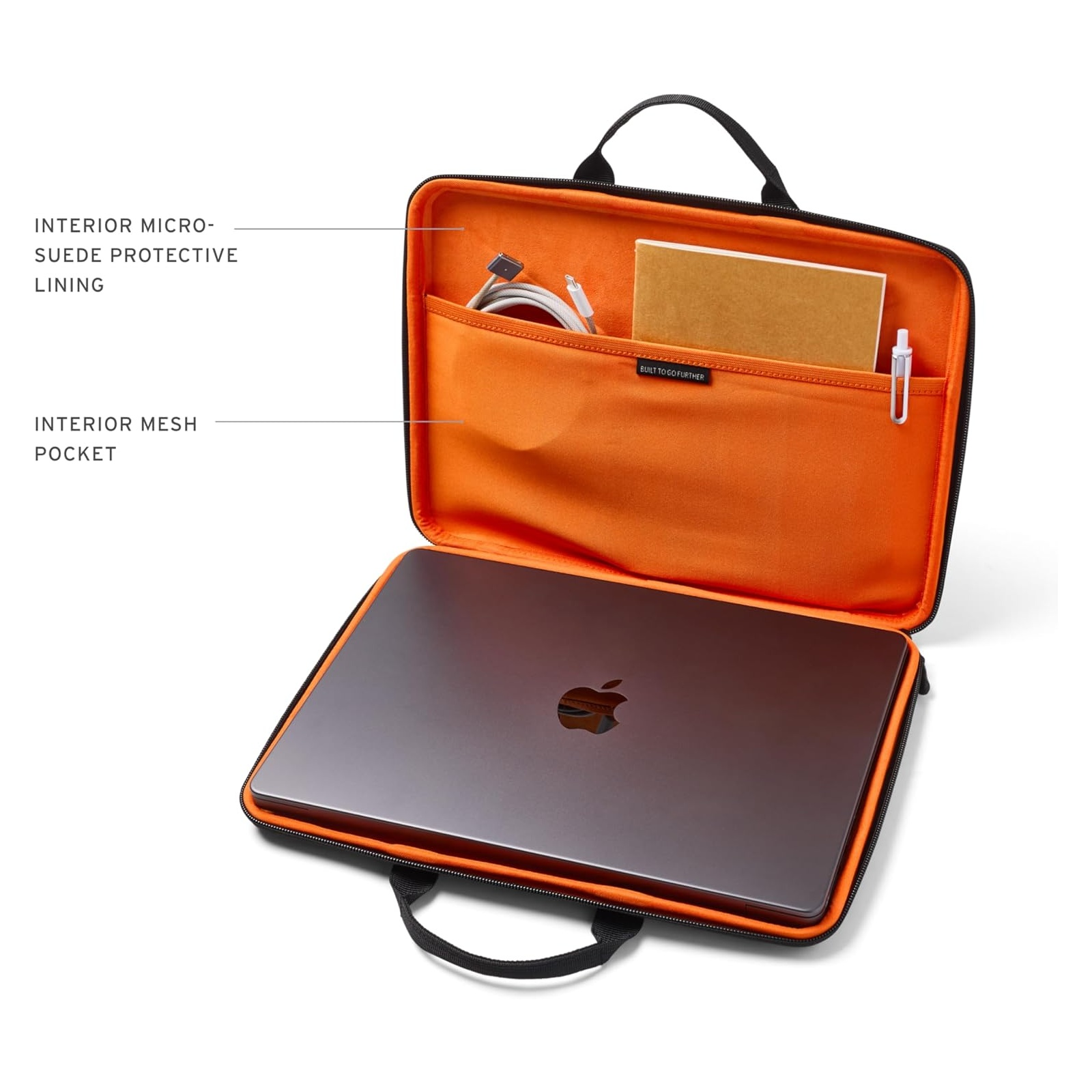 Otwarta torba na laptopa z pomarańczowym wnętrzem, pokazująca laptopa, kable, notatnik i długopis.