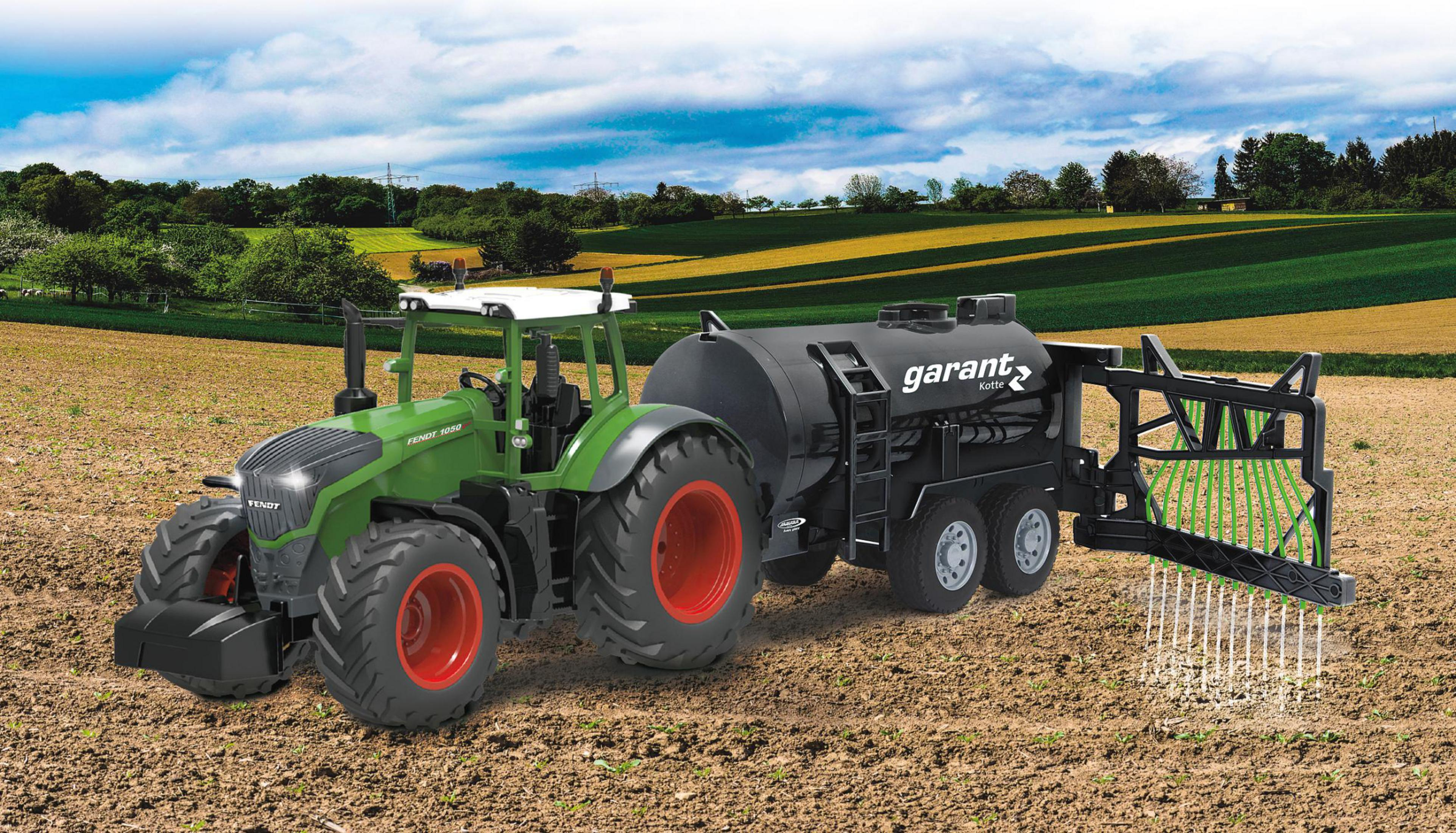 Grüner Traktor mit schwarzem Tankwagen auf einem Feld. Blaue Wolken am Himmel.