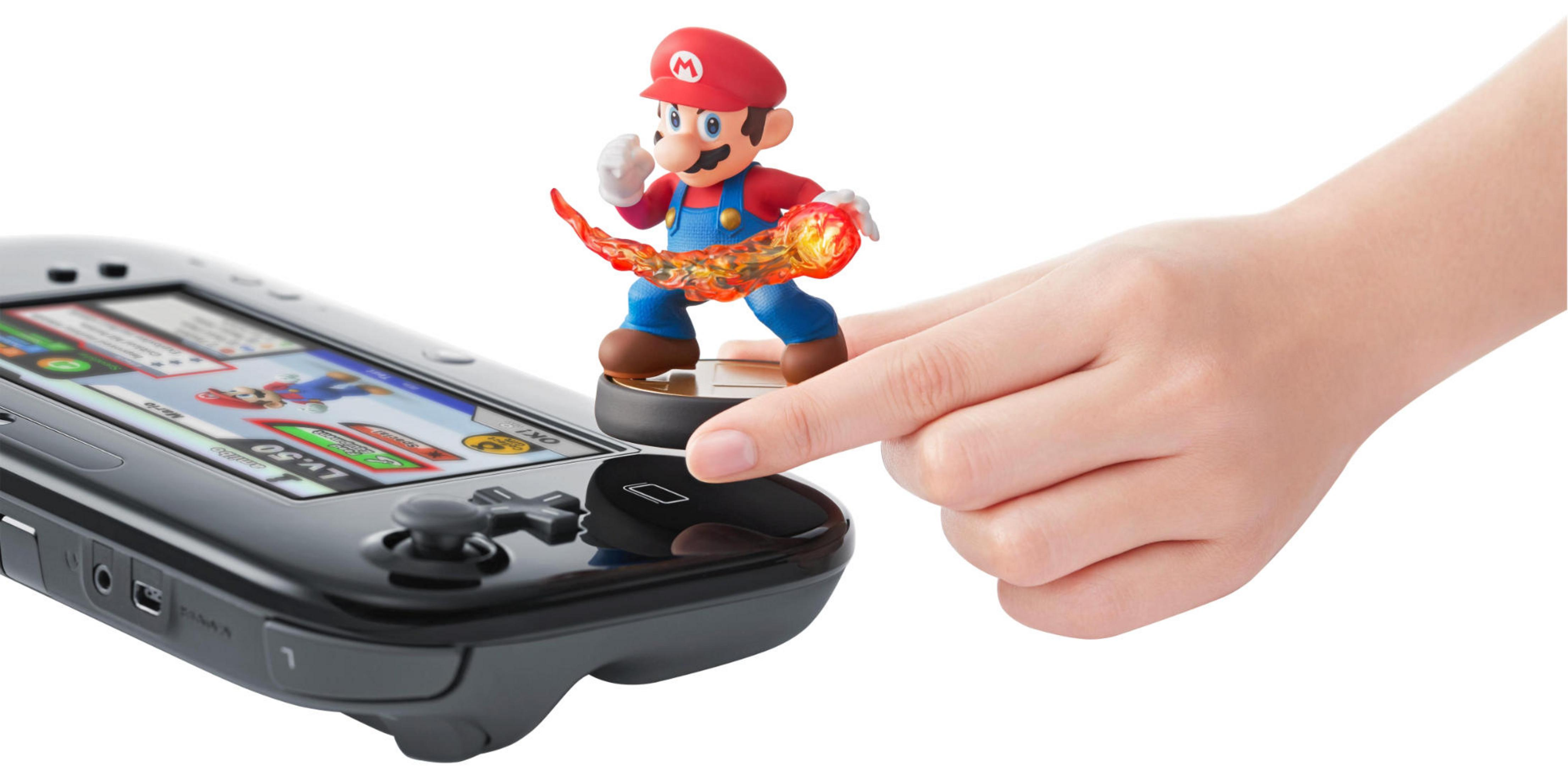 Figurine Mario avec attaque de feu sur une manette Nintendo Wii U actionnée par une main.