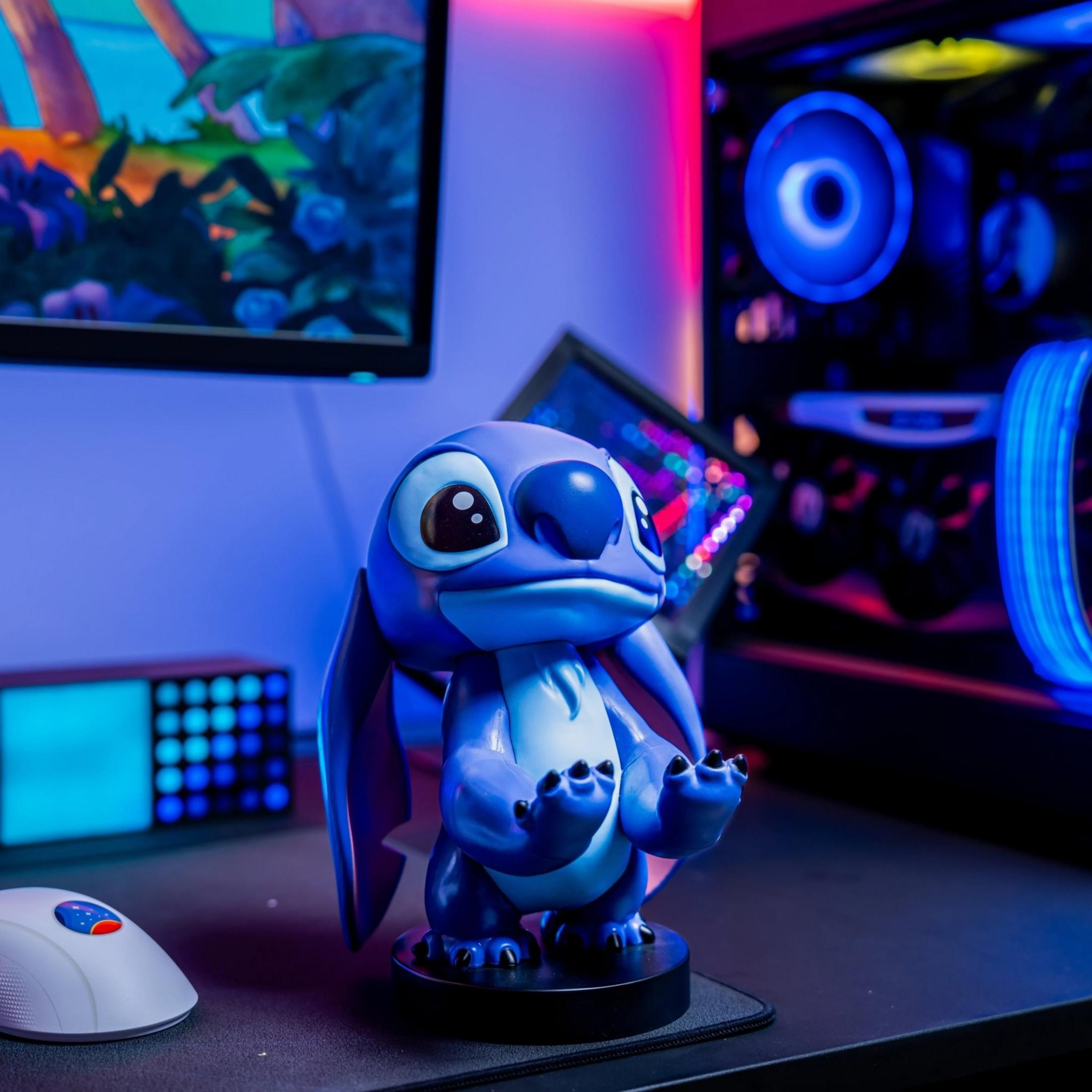 Una statuetta blu di Stitch si trova su una scrivania con un PC e un mouse.