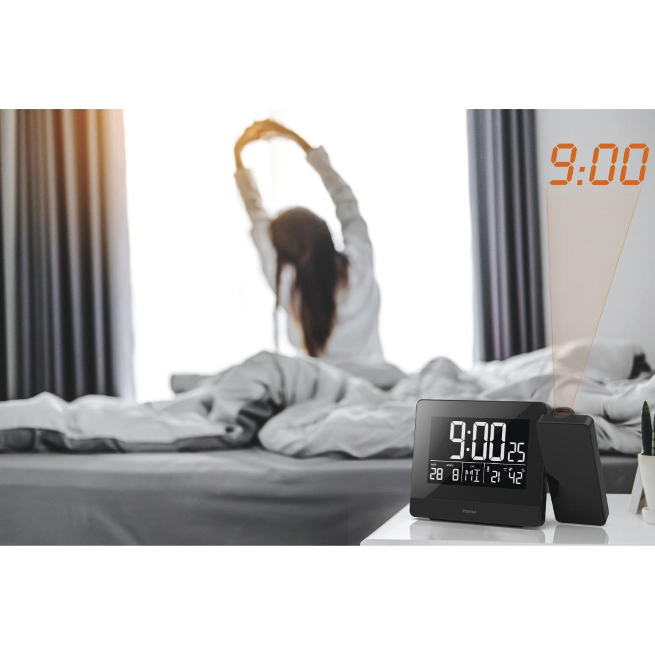 Una donna si stira a letto mentre una sveglia a proiezione mostra le 9:00.
