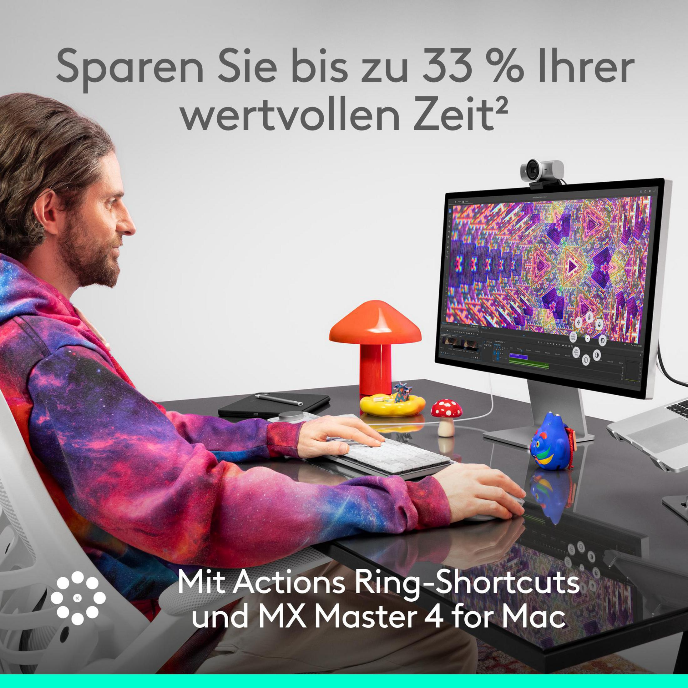 Man in colorful clothing at a desk looking at a monitor with colorful graphics.