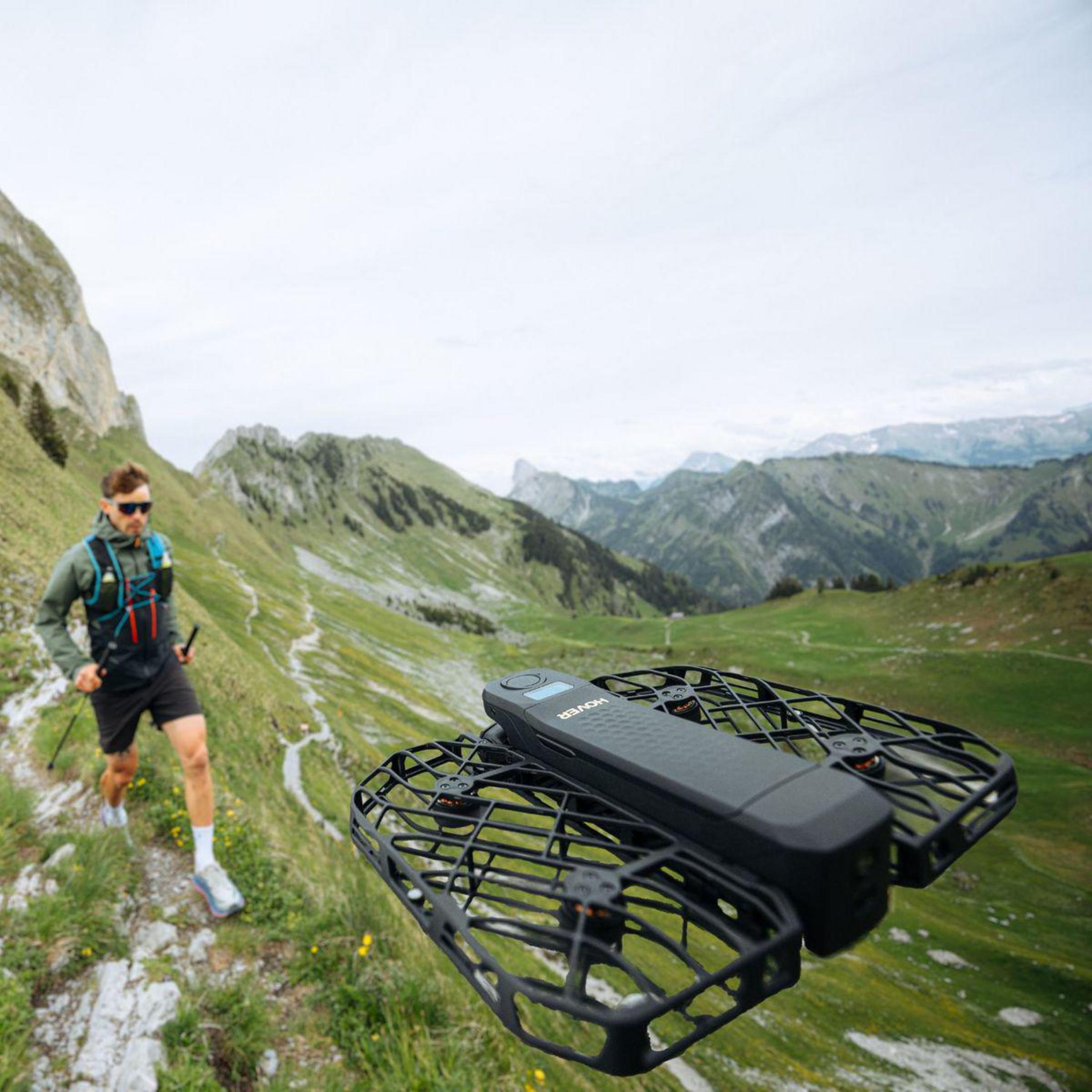 Un uomo corre su un sentiero di montagna, un drone vola davanti a lui.