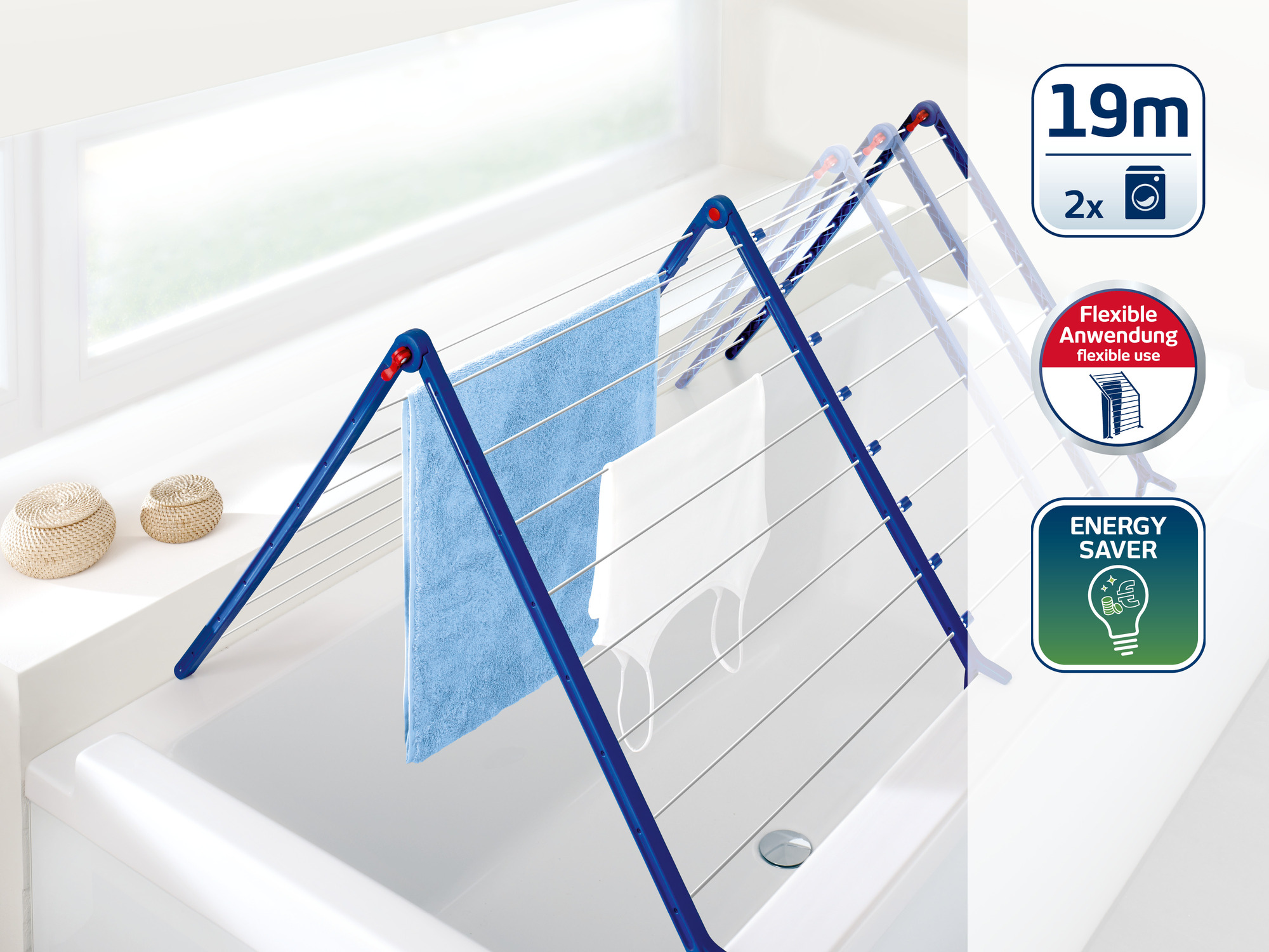 Ein blauer Wäscheständer mit Handtüchern und Kleidungsstücken, der über einer Badewanne steht.