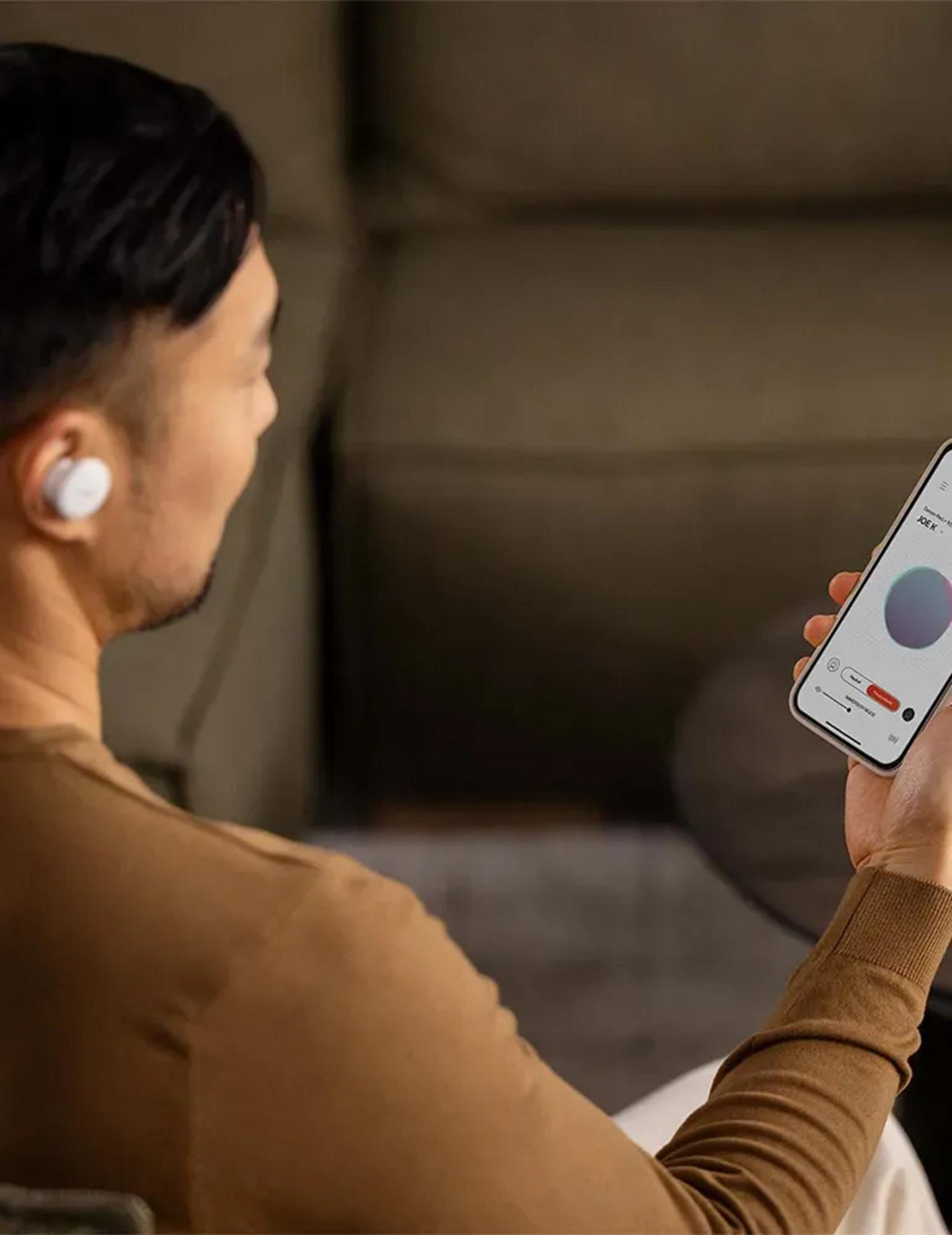 Uomo con auricolari bianchi tiene uno smartphone con app musicale.