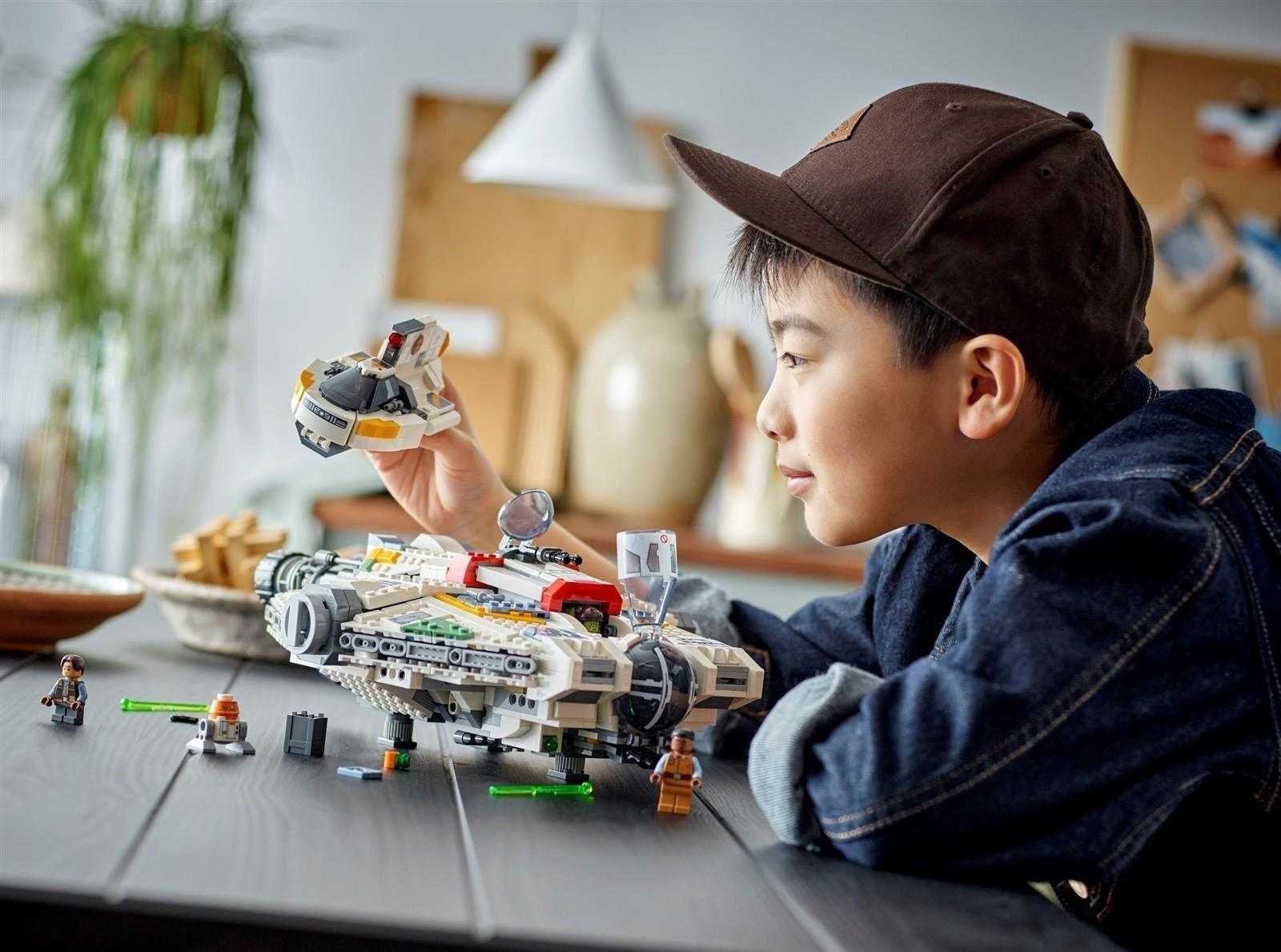 Ein Junge baut ein Raumschiff aus Lego-Steinen. Er hält ein kleines Teil.