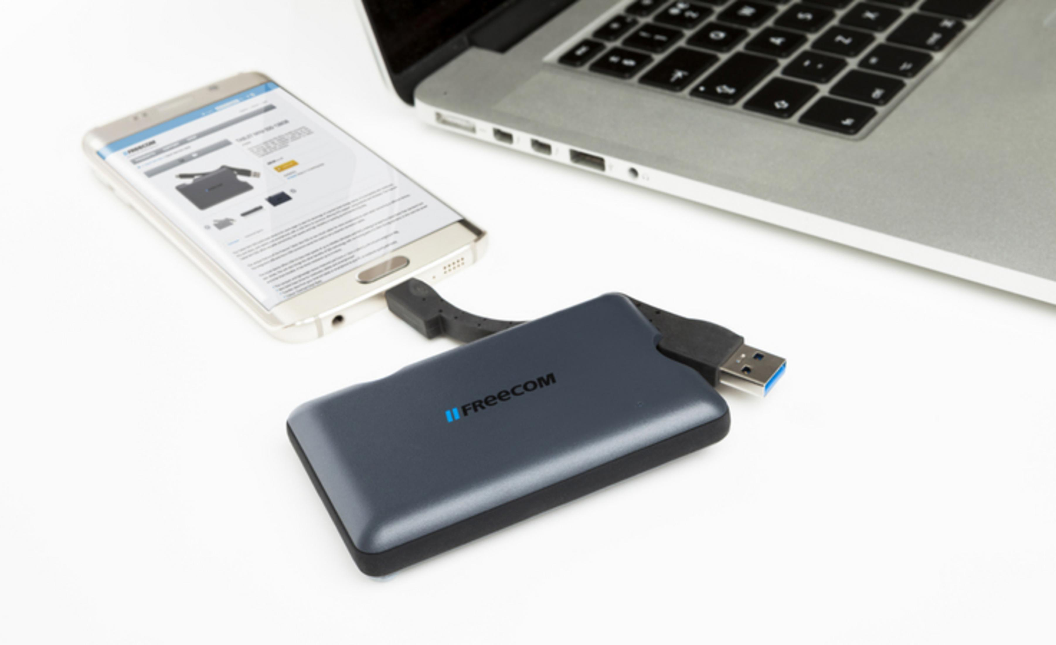 Un disco esterno si collega a uno smartphone accanto a un laptop.