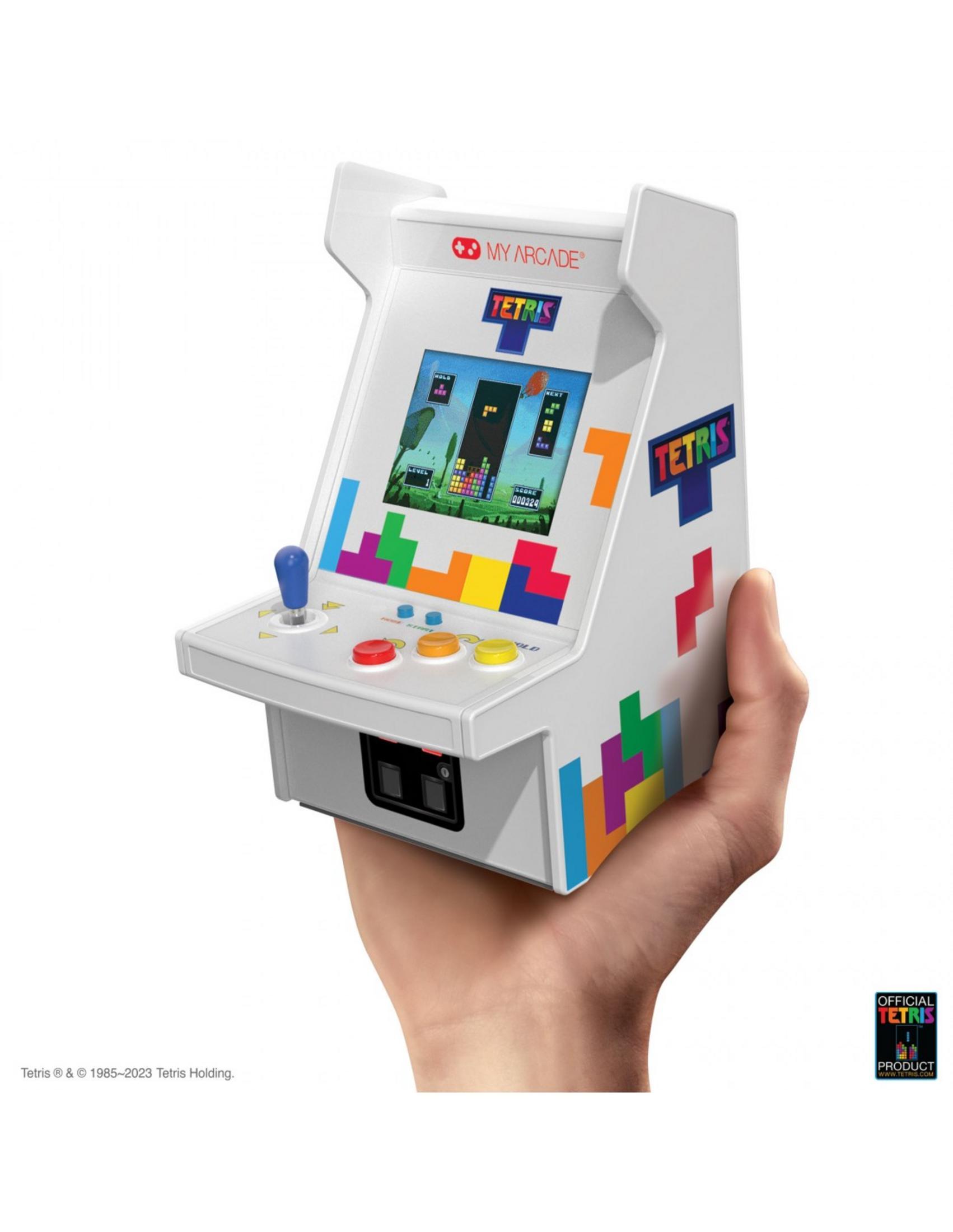Una macchina arcade Tetris bianca con joystick e pulsanti, tenuta da una mano.