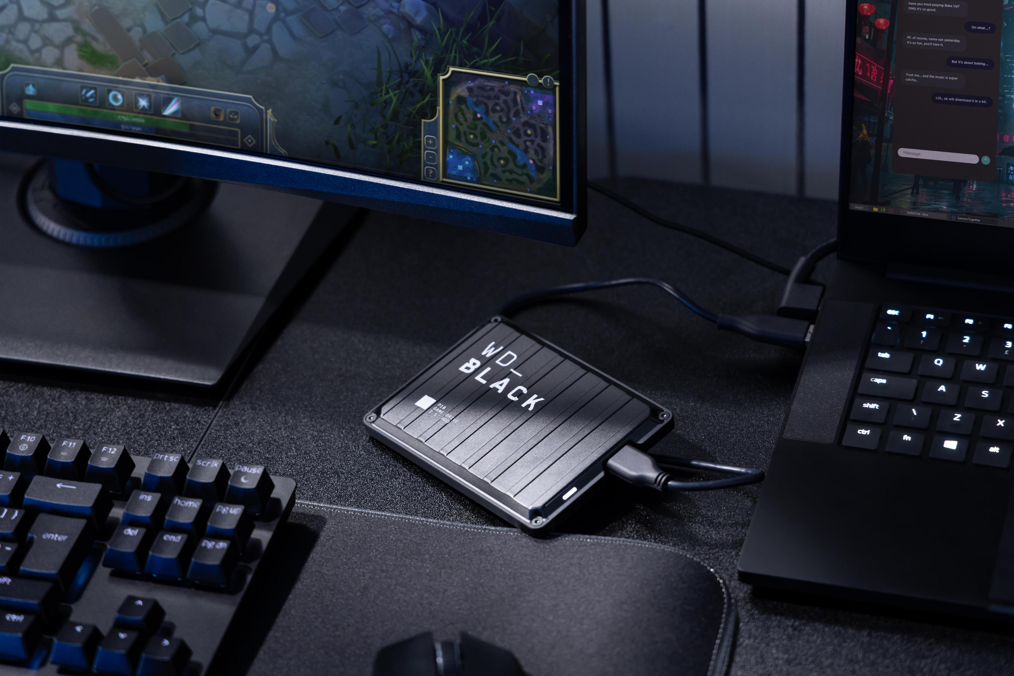 Unità esterna WD_BLACK collegata a un laptop vicino a un setup per PC da gioco.