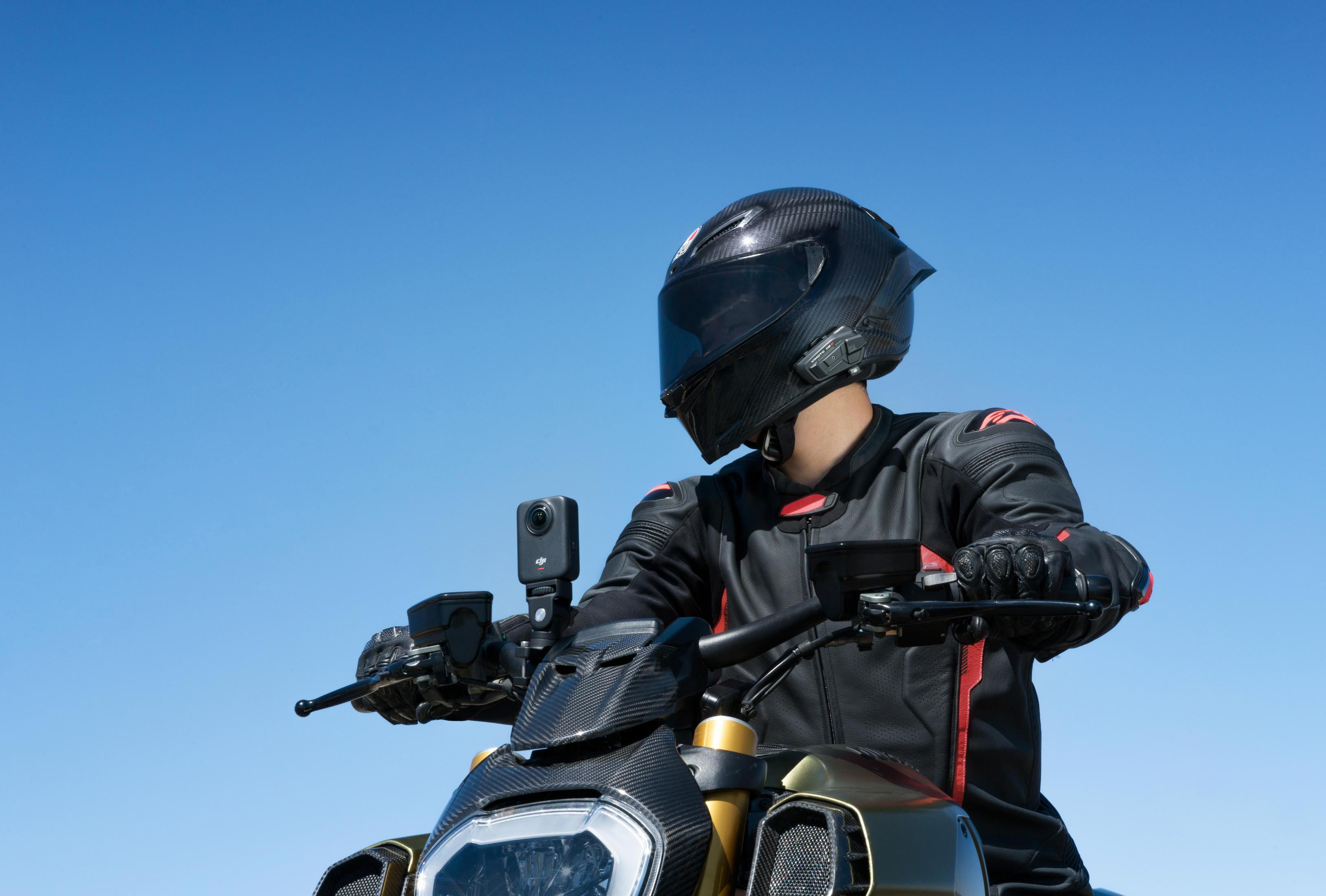 Motorradfahrer in schwarzer Lederkleidung mit roter Akzentuierung auf einem Motorrad.