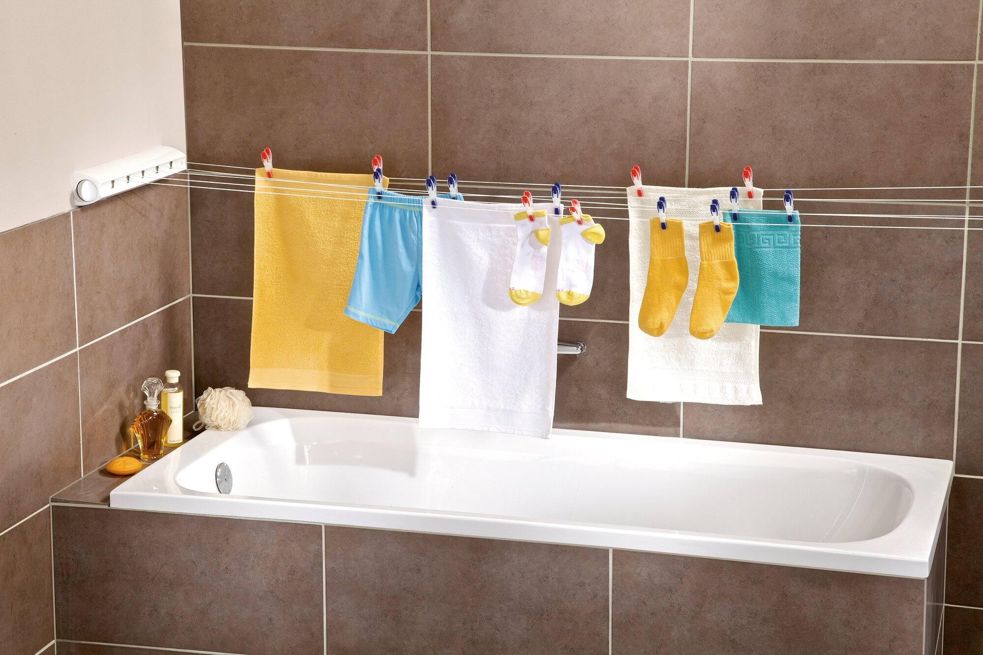 Ein Badezimmer mit einer ausziehbaren Wäscheleine, an der Handtücher und Socken trocknen.