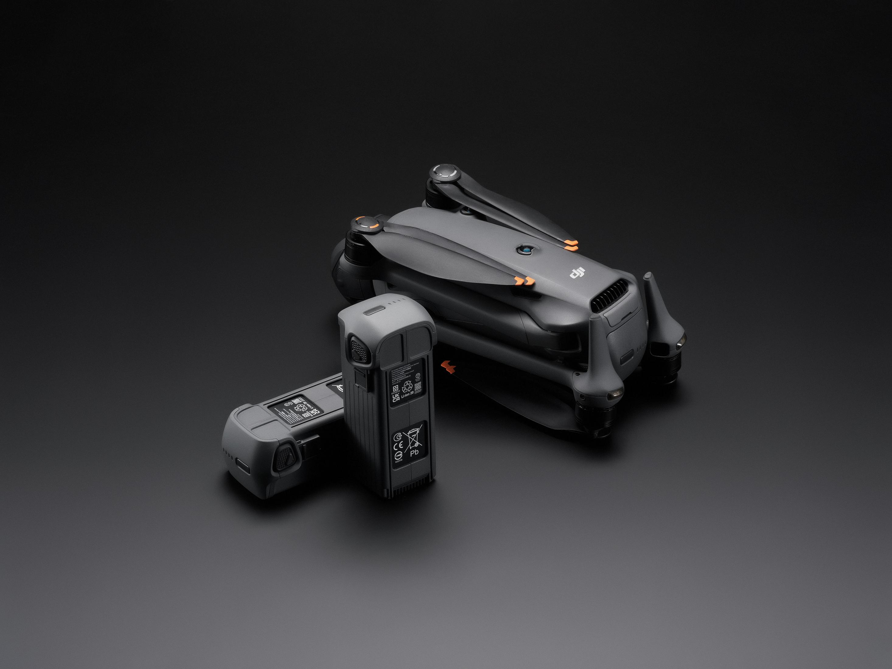 Un modello di drone DJI grigio con due batterie su sfondo nero.